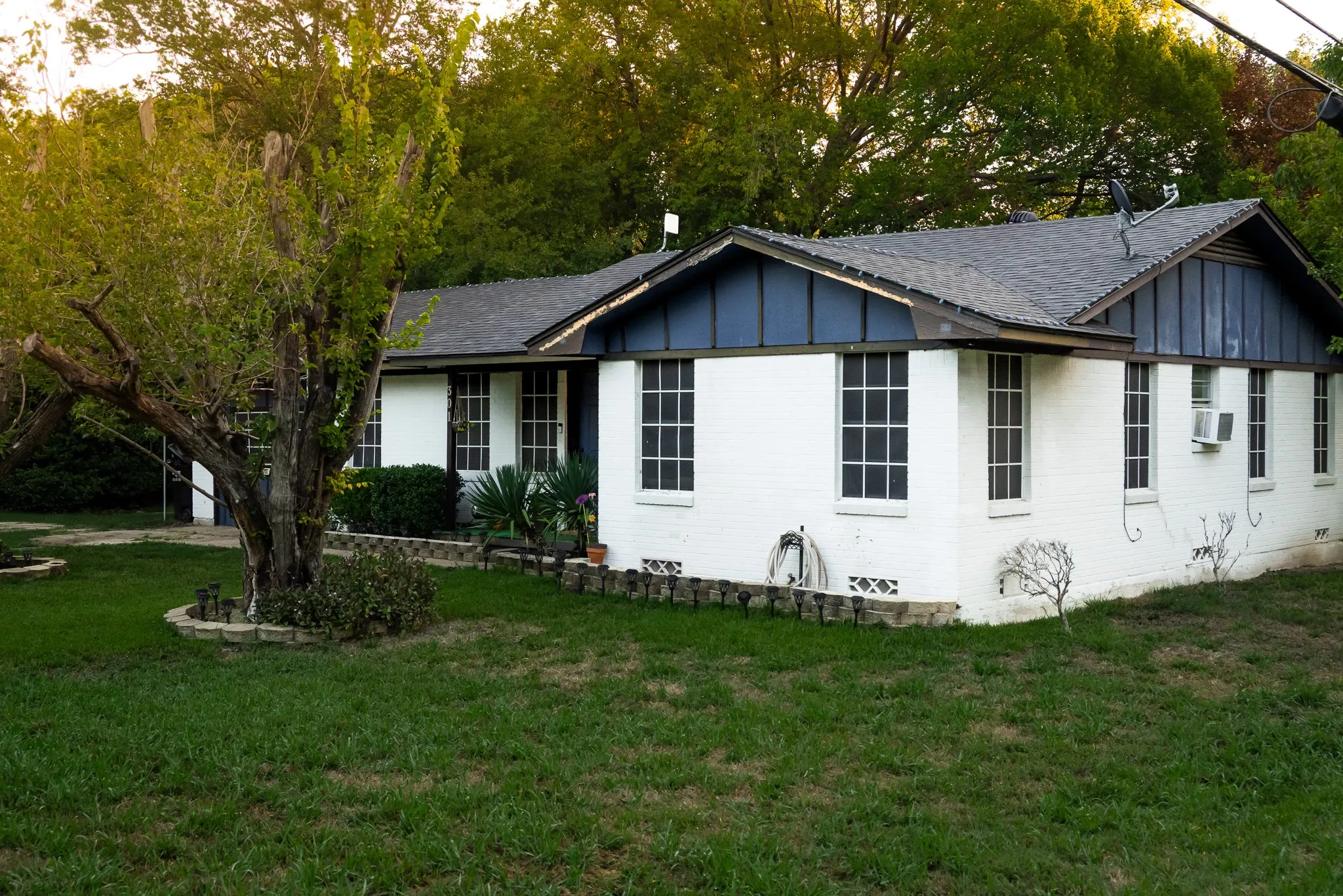 Painted brick exterior featuring dark vertical siding accents, multi-pane windows, and a composition shingle roof