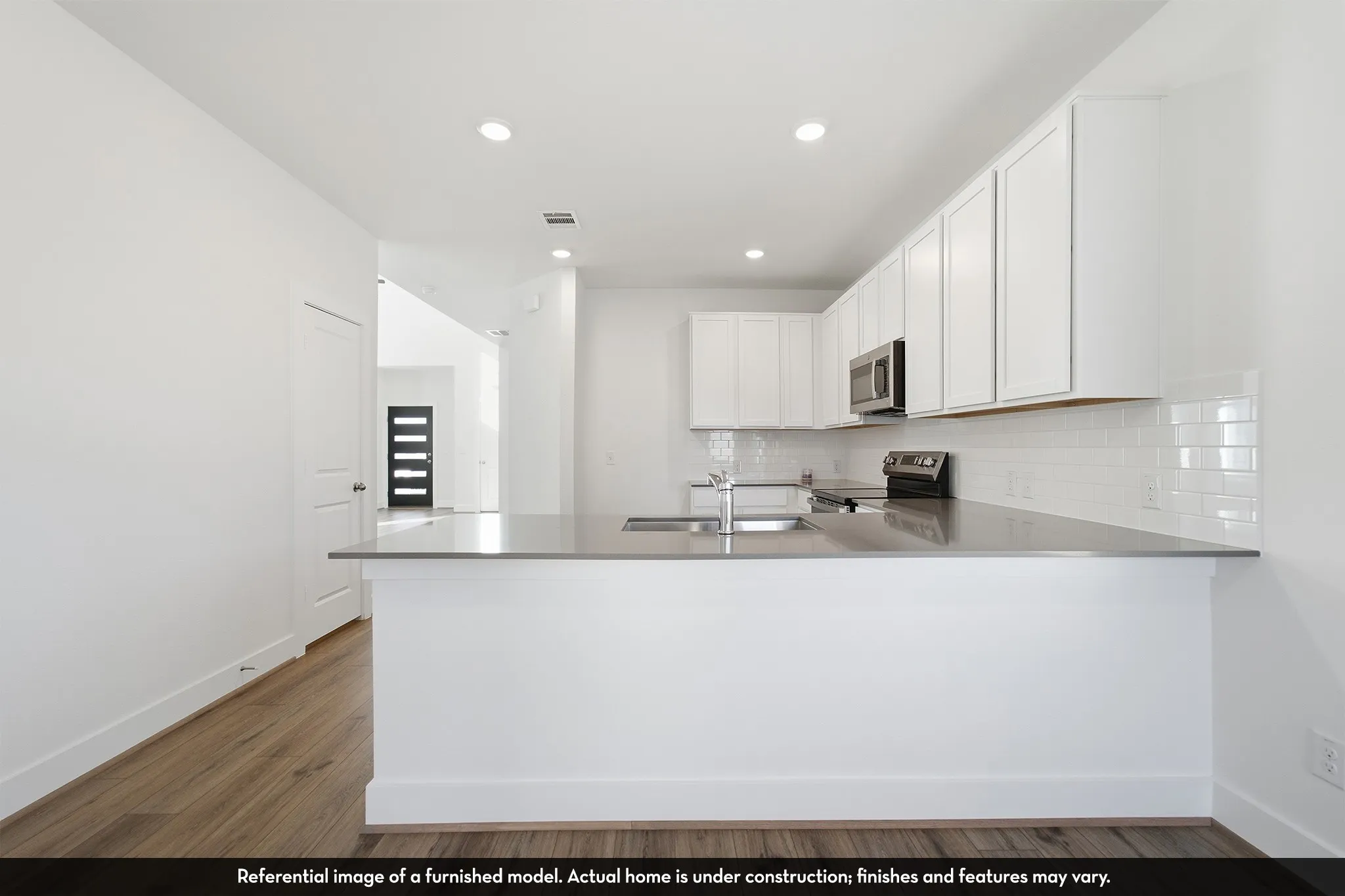 Kitchen featuring white shaker-style cabinetry, neutral solid-surface countertops, white subway tile backsplash, recessed ceiling lighting, and wood-finish flooring