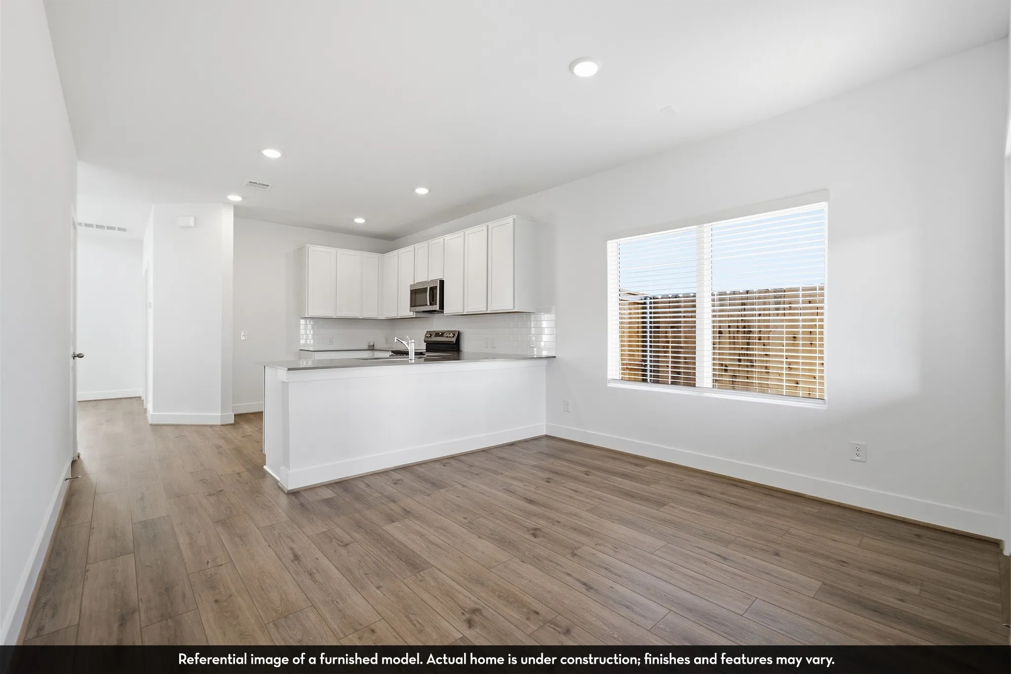 Kitchen featuring white shaker-style cabinetry, a stone-surface countertop, stainless steel over-the-range microwave, and wood-finish flooring