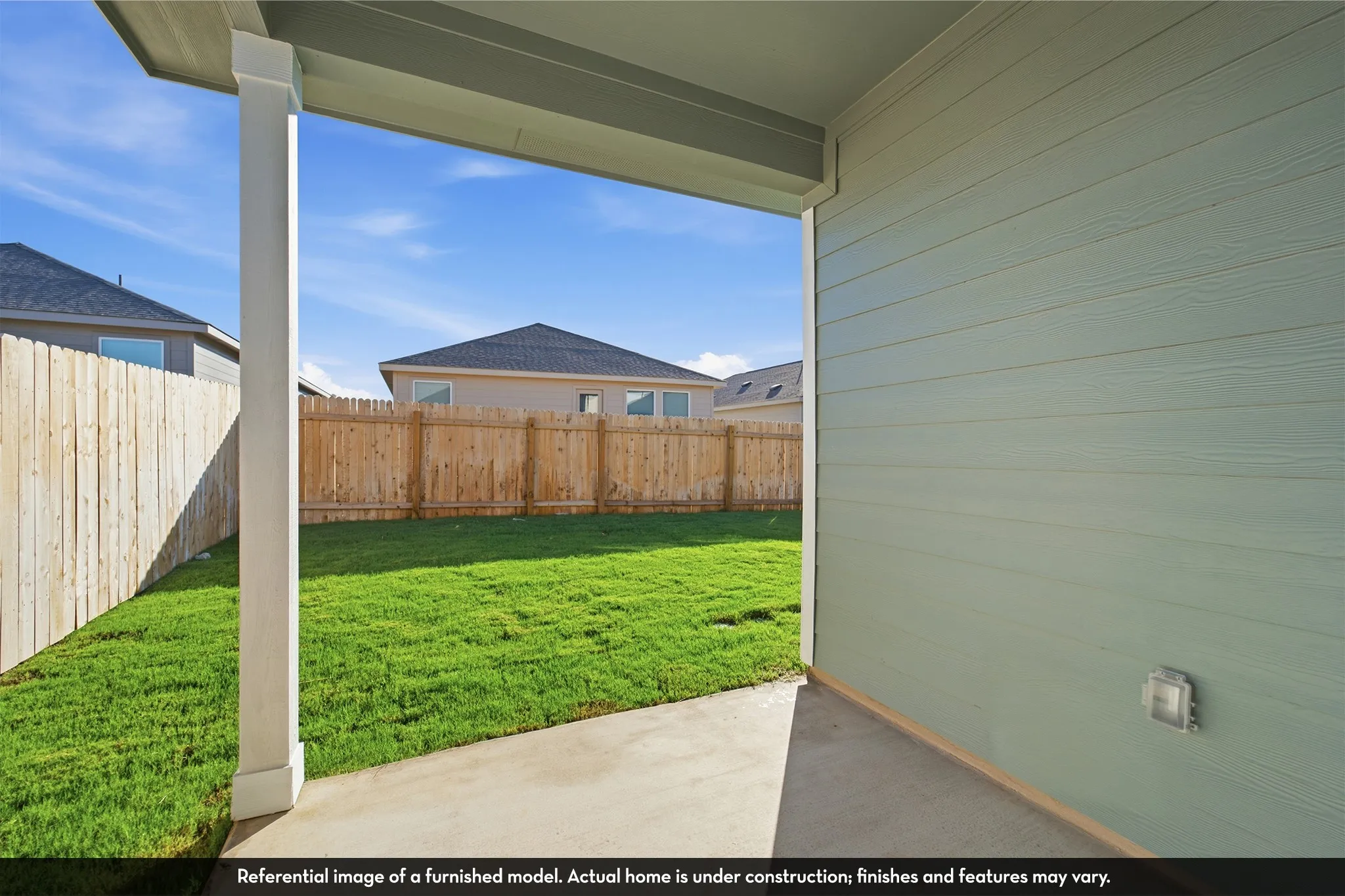 Covered concrete patio with horizontal lap siding, square support column, and wood privacy fencing enclosing a grass lawn