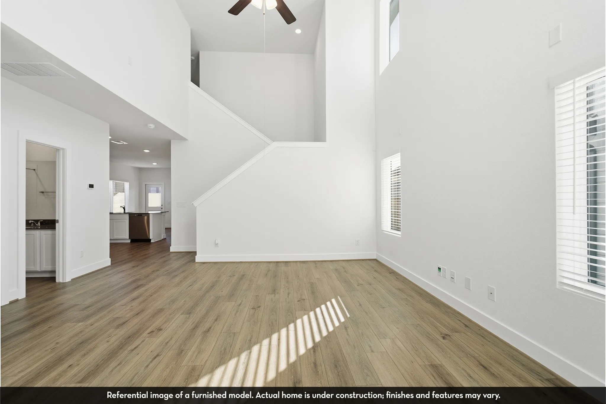 Double-height ceiling, wood-finish flooring, recessed lighting, and wall-mounted ceiling fan