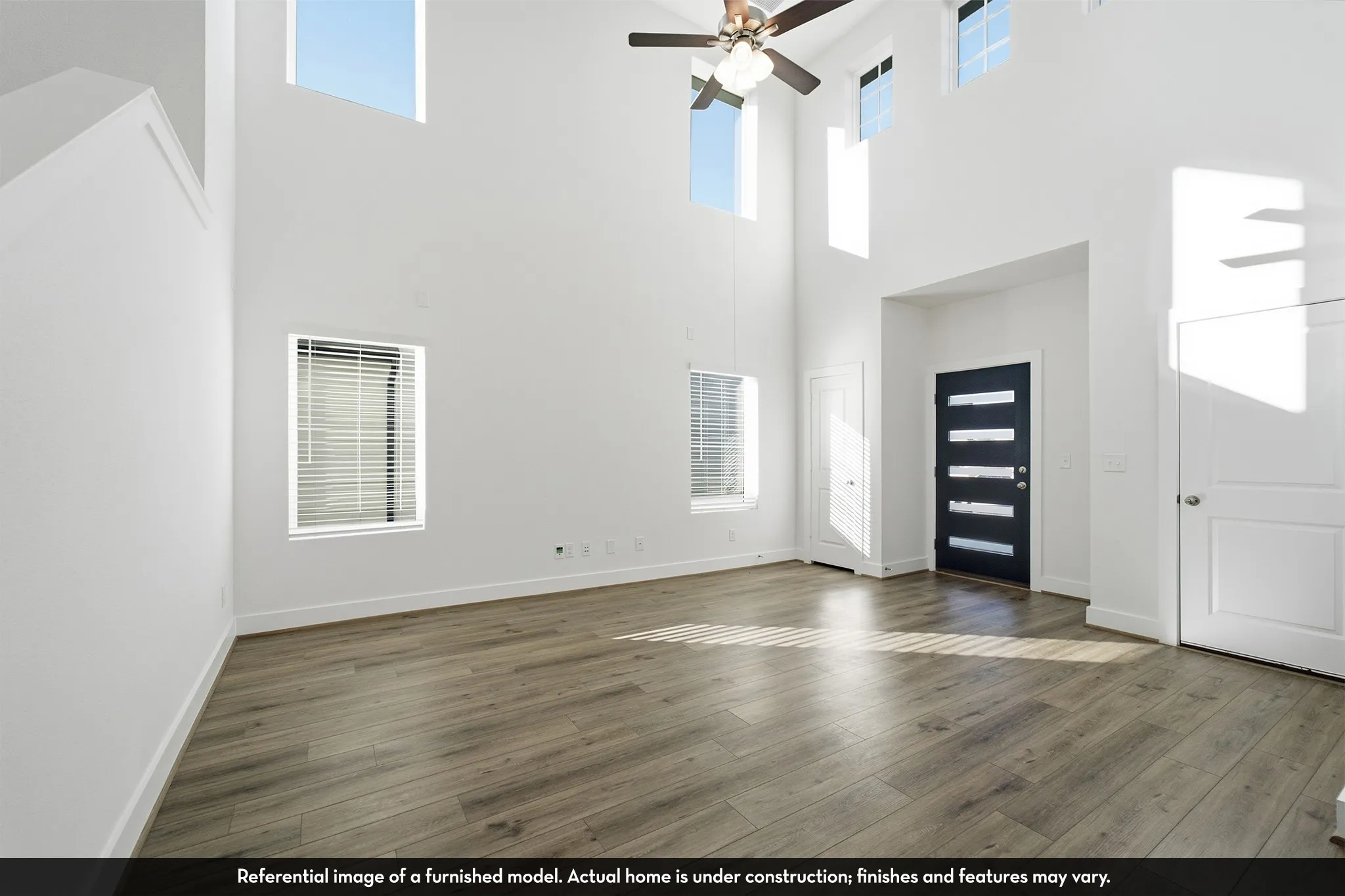 Vaulted ceilings featuring multi-level windows, wood-finish flooring, and a contemporary entry door with horizontal glass inserts