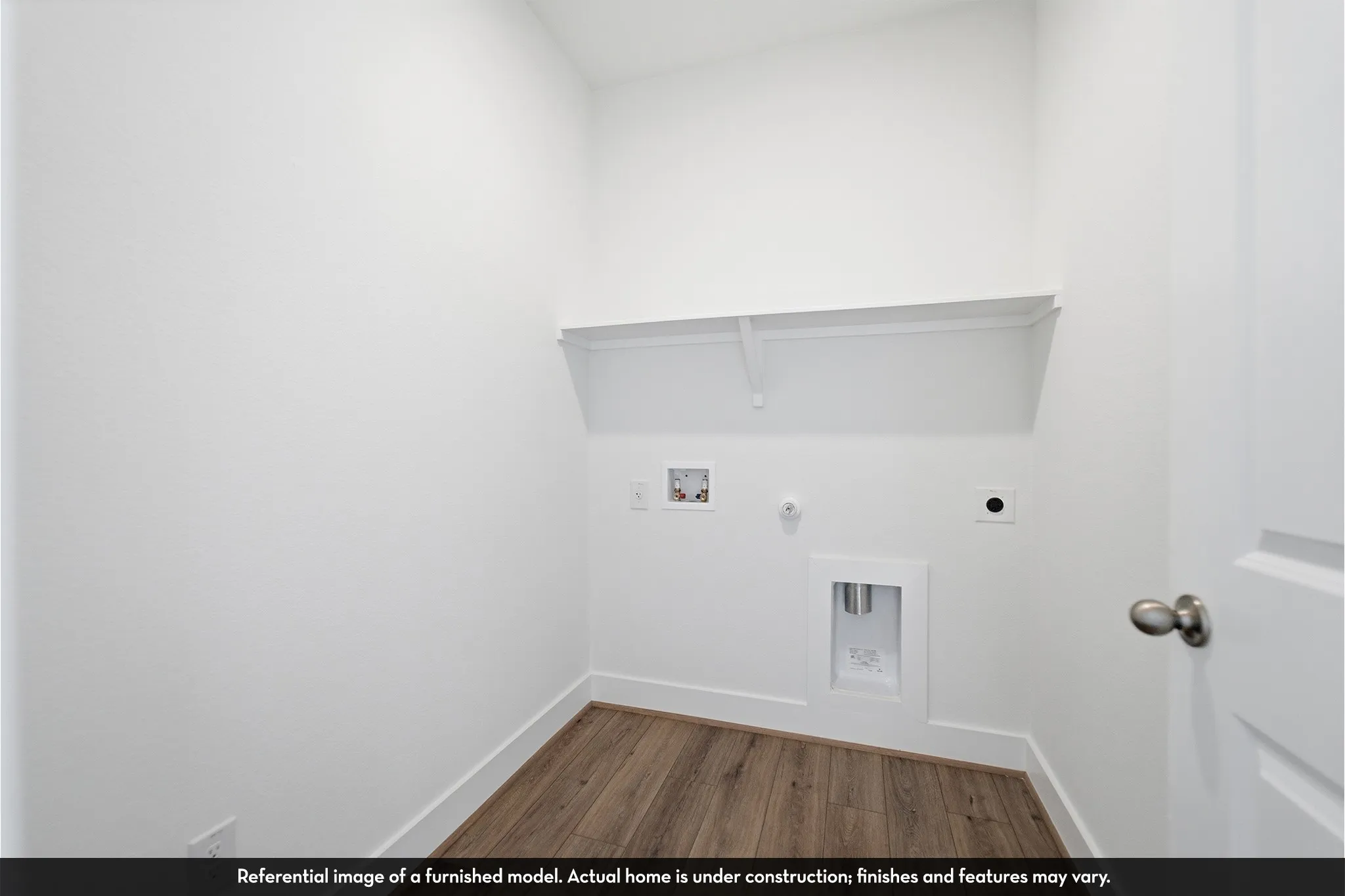 Utility area featuring wood-finish flooring, a built-in wall shelf, and laundry hookups