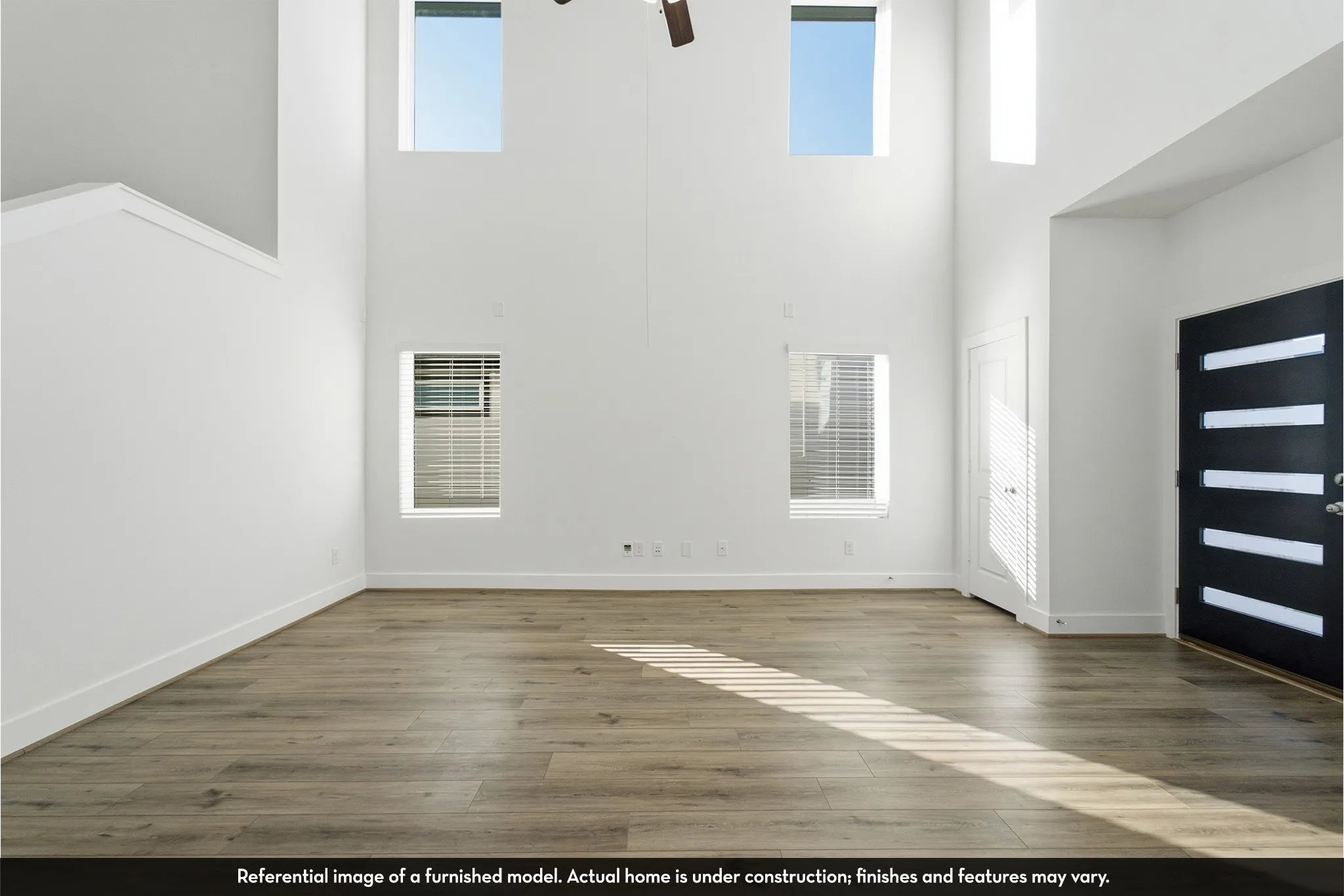 Double-height ceiling, wood-finish flooring, multi-paneled front door with glass inserts, and large windows