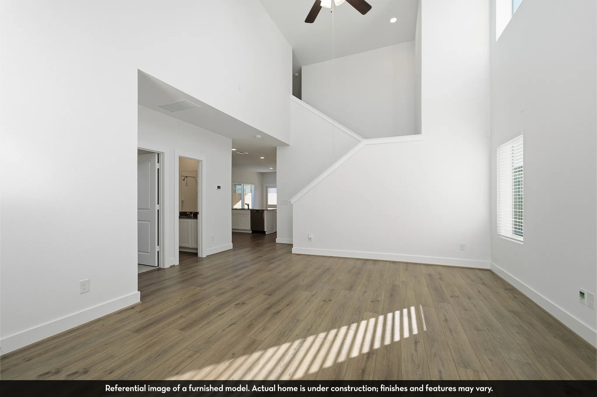 Double-height ceilings, wood-finish flooring, recessed lighting, and a ceiling fan