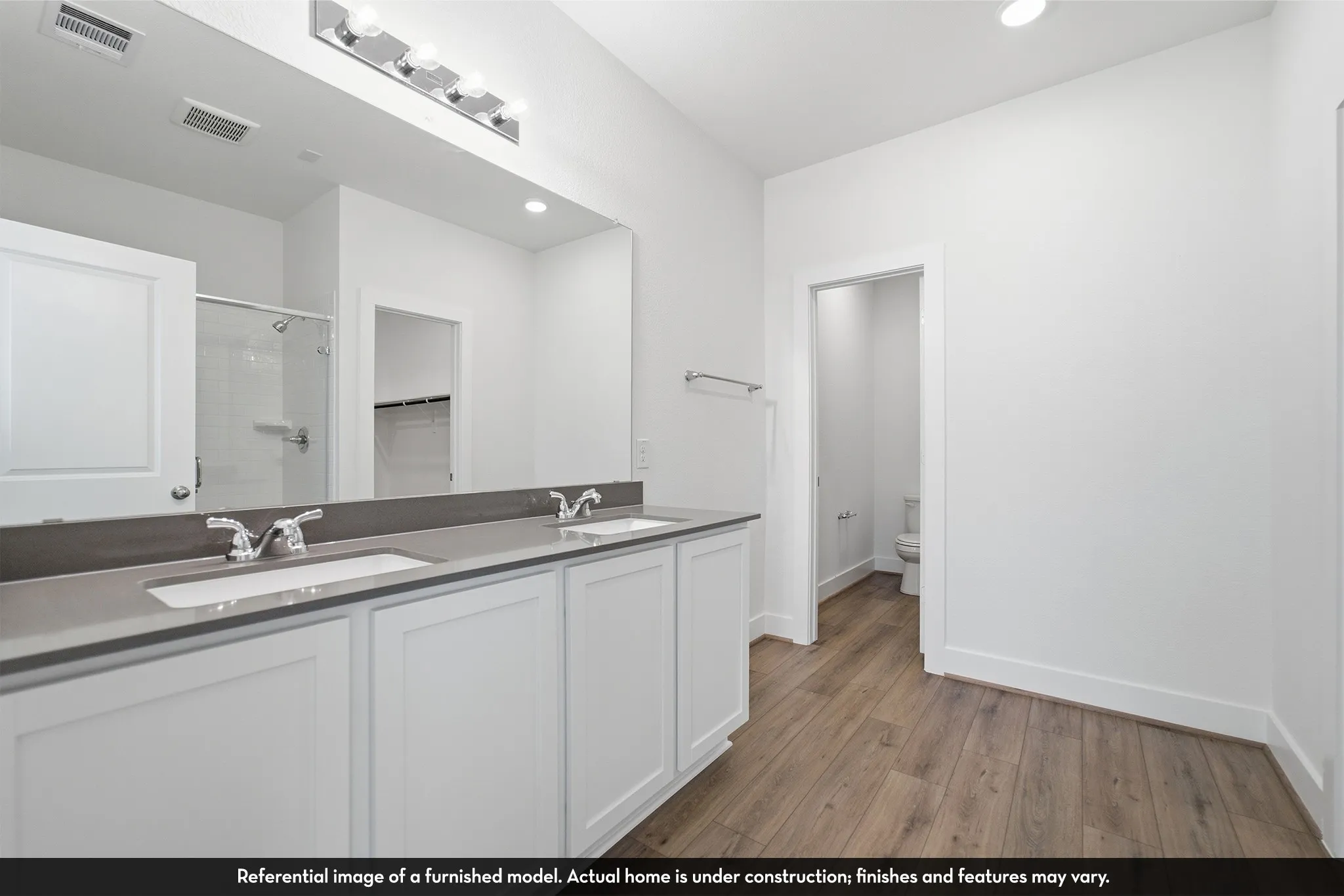 Double-sink vanity featuring shaker-style cabinetry, solid-surface countertop, and wood-finish flooring
