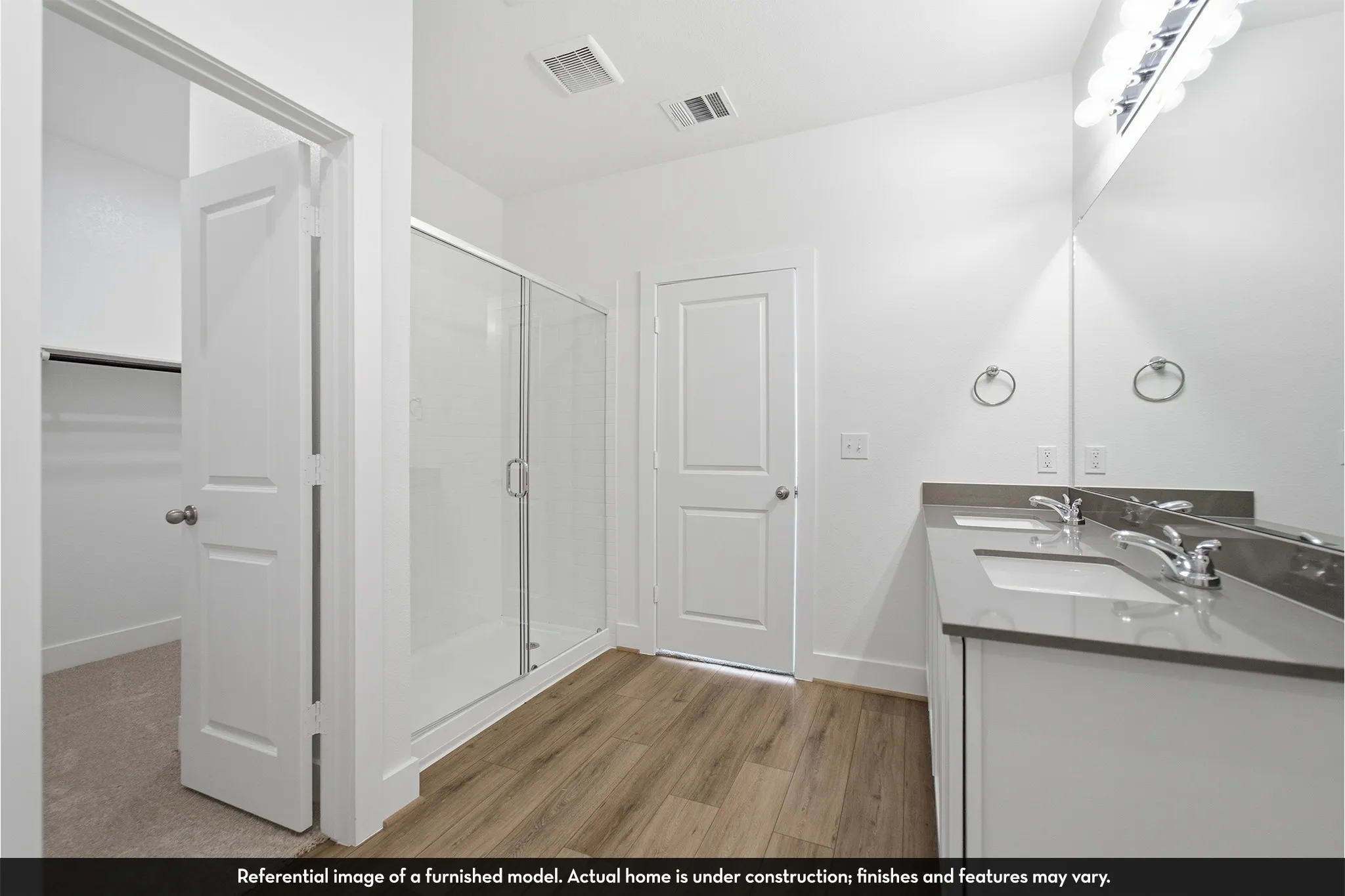 Dual-sink vanity with solid-surface countertop, glass-enclosed shower, and wood-finish flooring