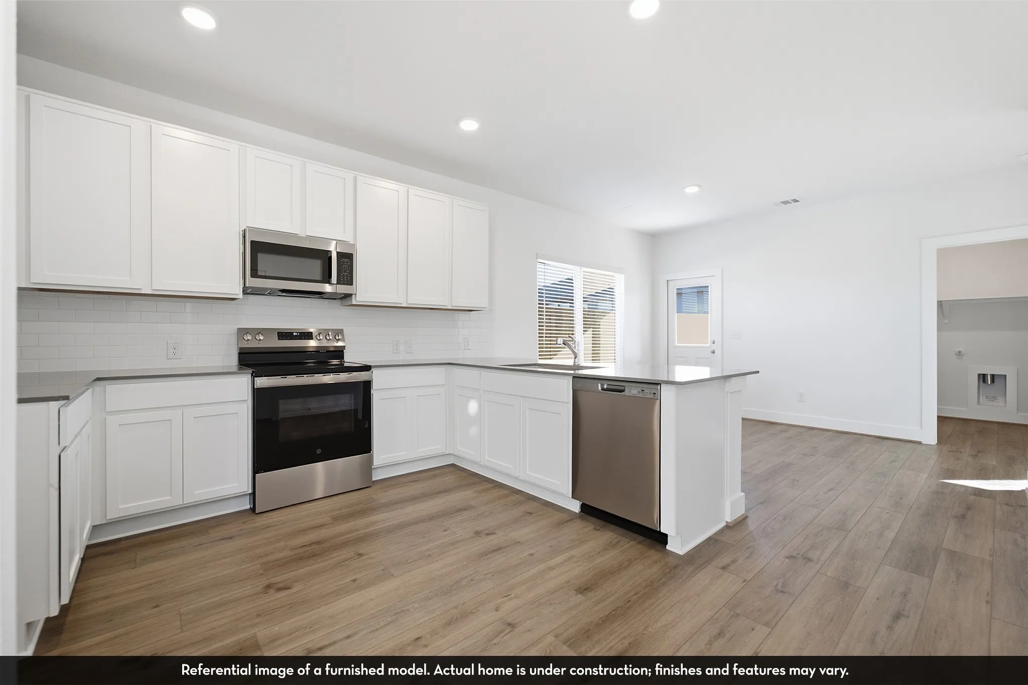 Kitchen featuring white Shaker-style cabinetry, stainless steel appliances, white subway tile backsplash, solid-surface countertops, and wood-finish flooring