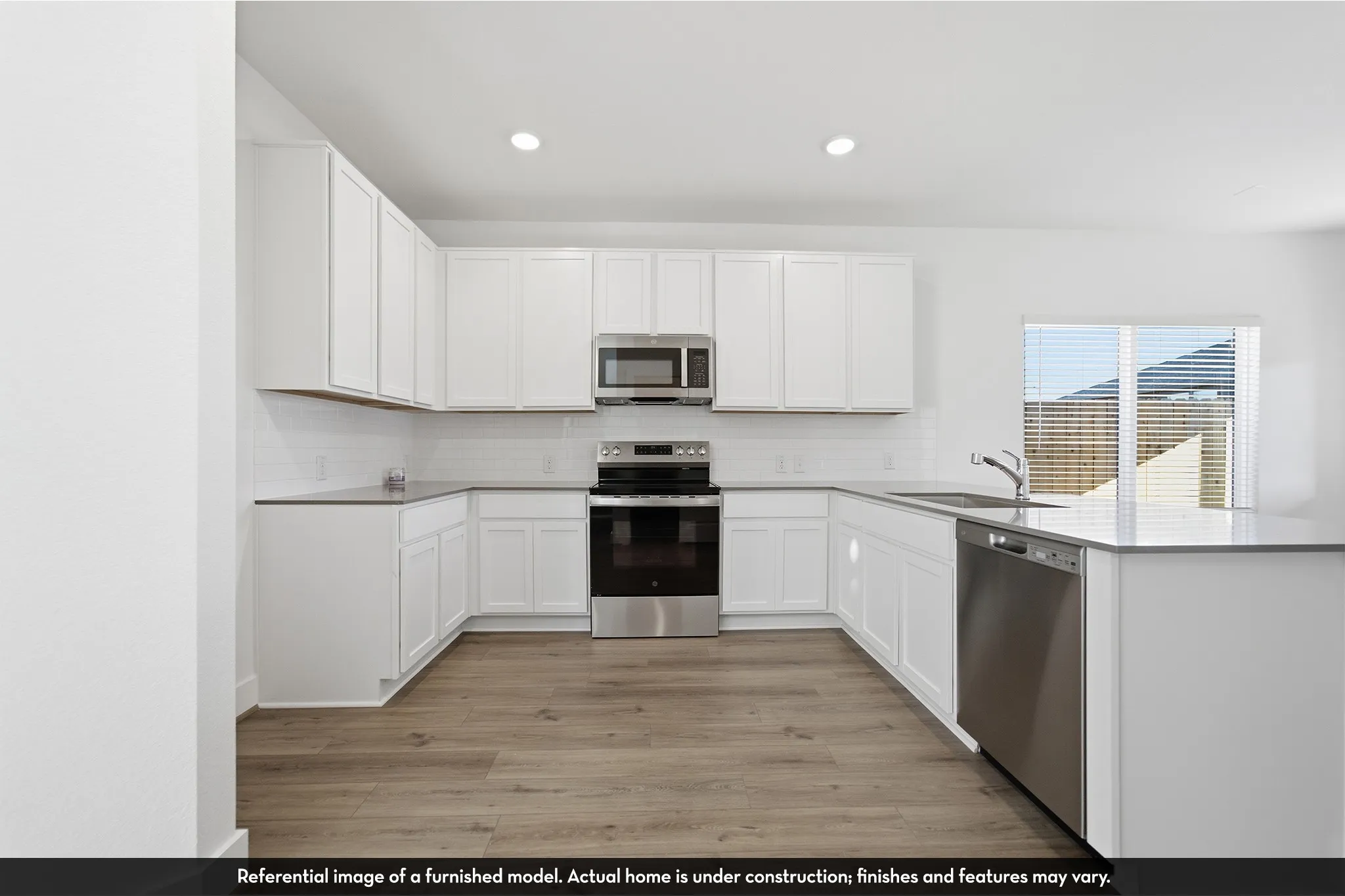 Kitchen featuring white shaker-style cabinetry, stainless steel appliances, quartz countertops, subway tile backsplash, and wood-finish flooring