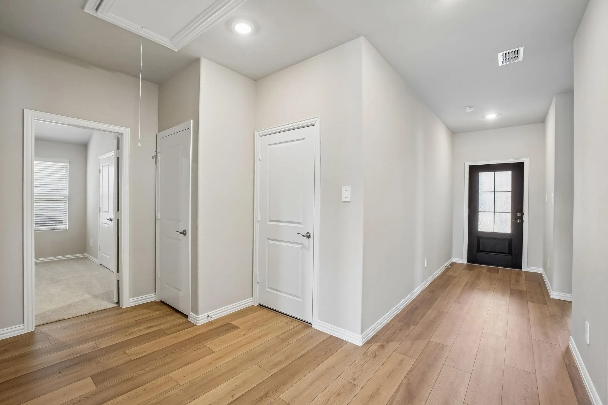 Interior entryway featuring wood-finish flooring, recessed lighting, and a dark-toned exterior door with glass panes
