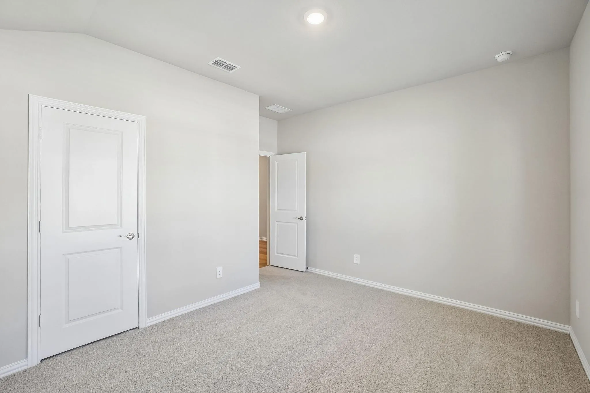 Neutral-toned interior space featuring light-colored wall paint, plush carpeting, multi-panel doors with brushed-nickel hardware, and recessed lighting