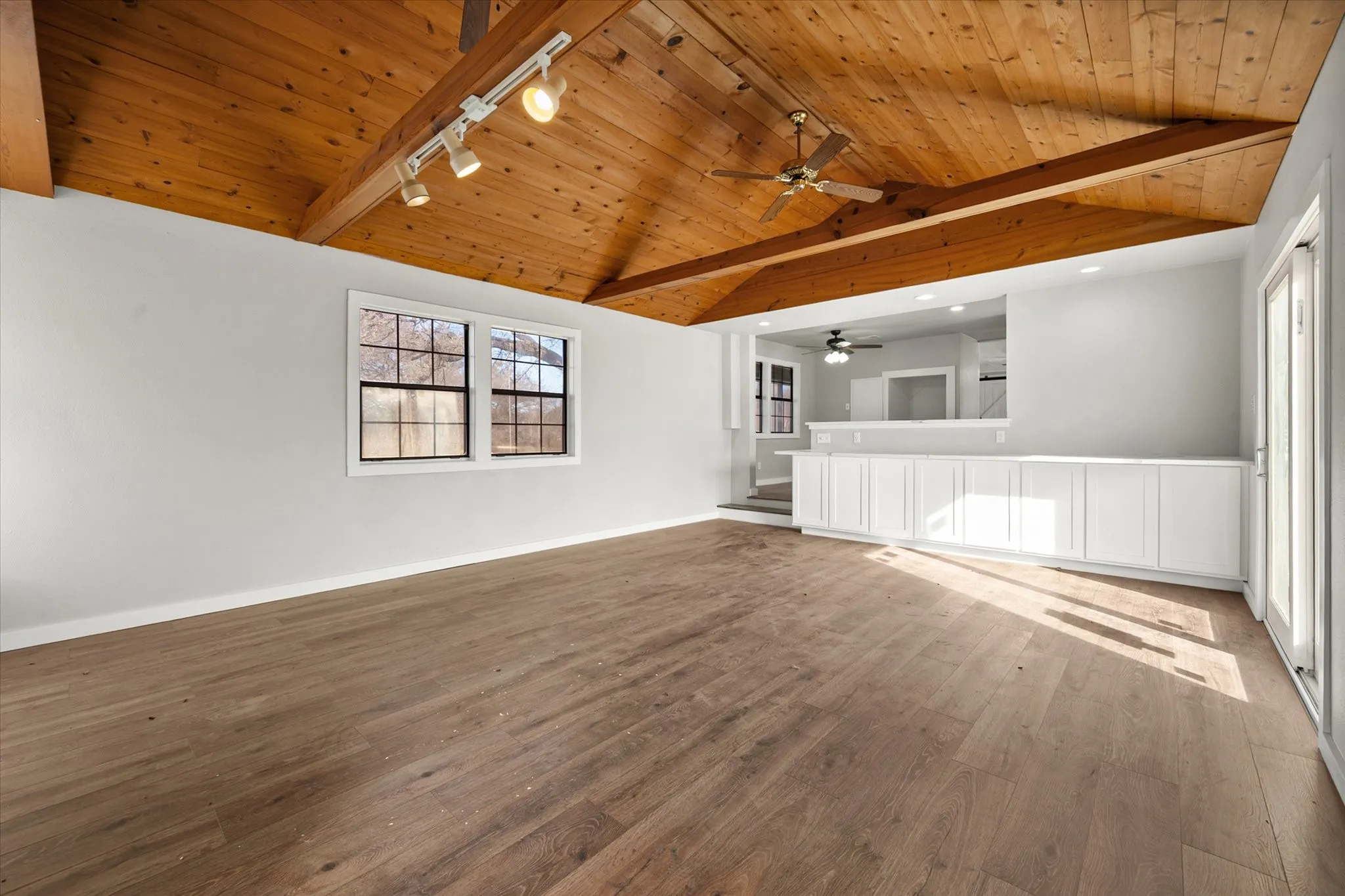 Vaulted wood-paneled ceiling, exposed wood beams, wood-finish flooring, white built-in cabinetry, and white framed​​‌​​​​‌​​‌‌​‌‌​​​‌‌​‌​‌​‌​​​‌​​ windows