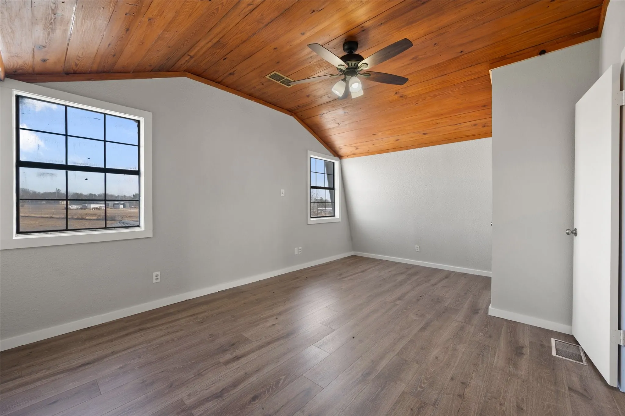 Vaulted wood-paneled ceiling, wood-finish flooring, ceiling fan, and multiple windows