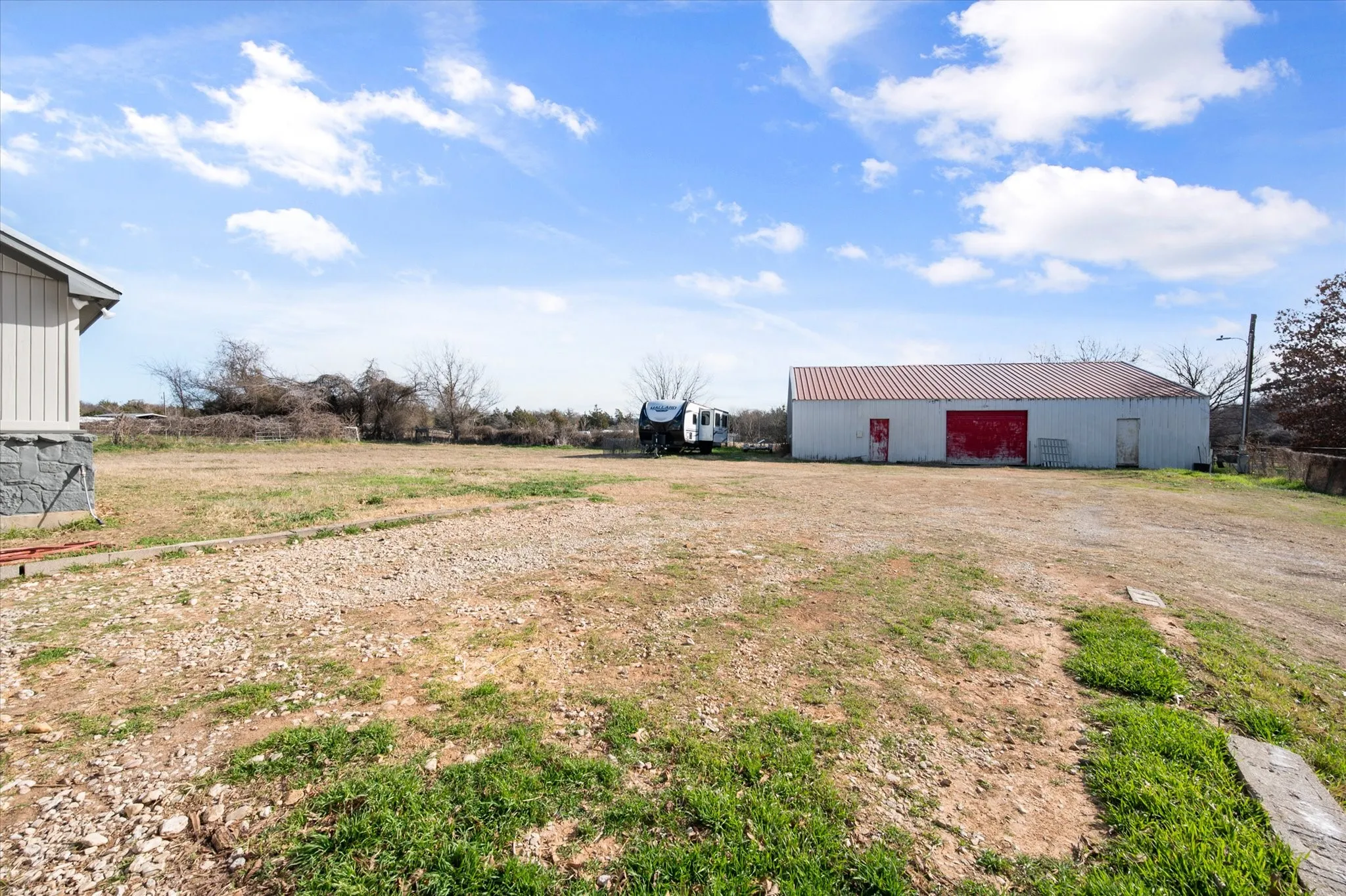 Expansive open land with a metal outbuilding featuring a red roll-up door