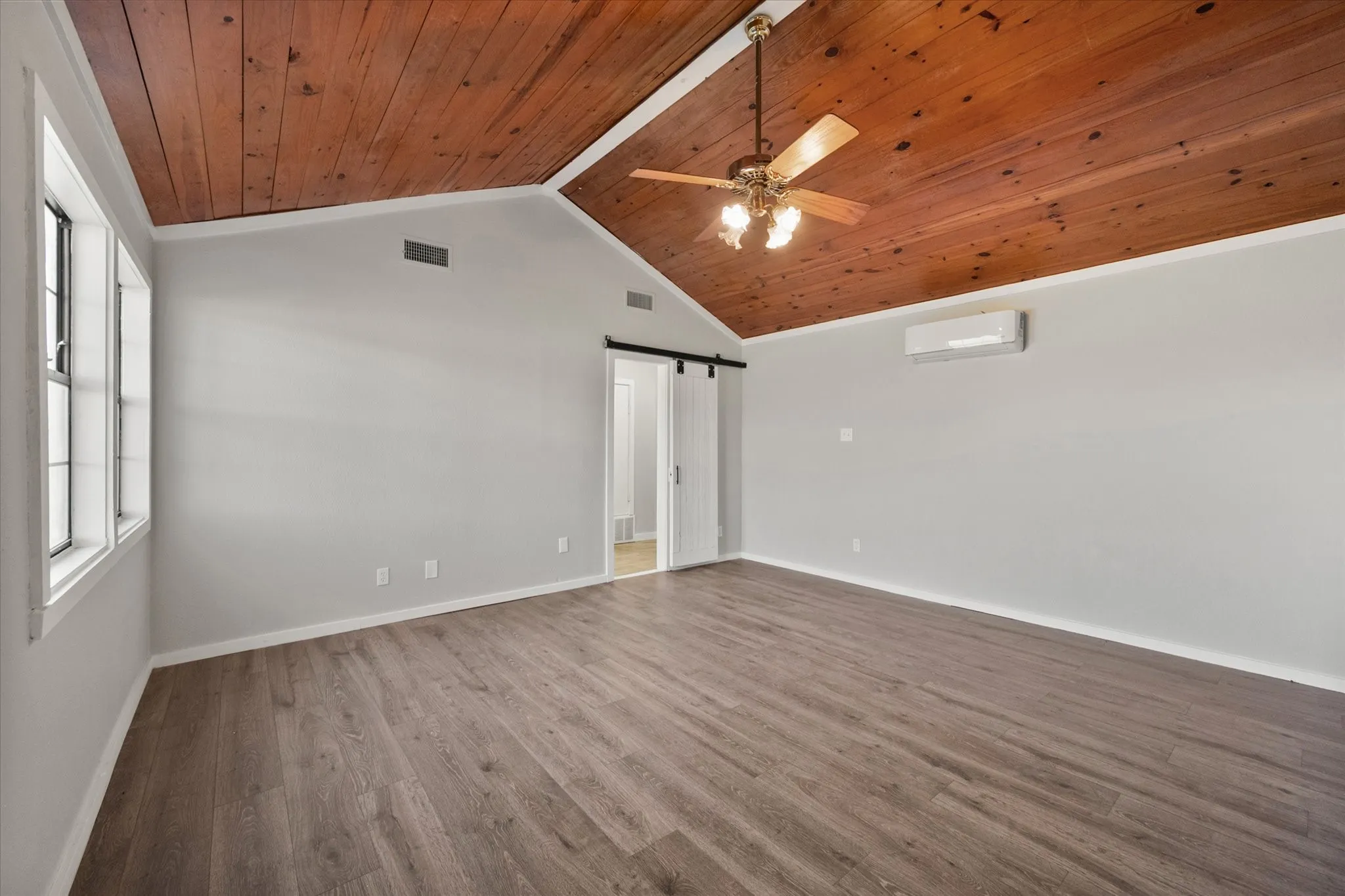 Vaulted wood-plank ceiling, wood-finish flooring, windows, and a ceiling fan