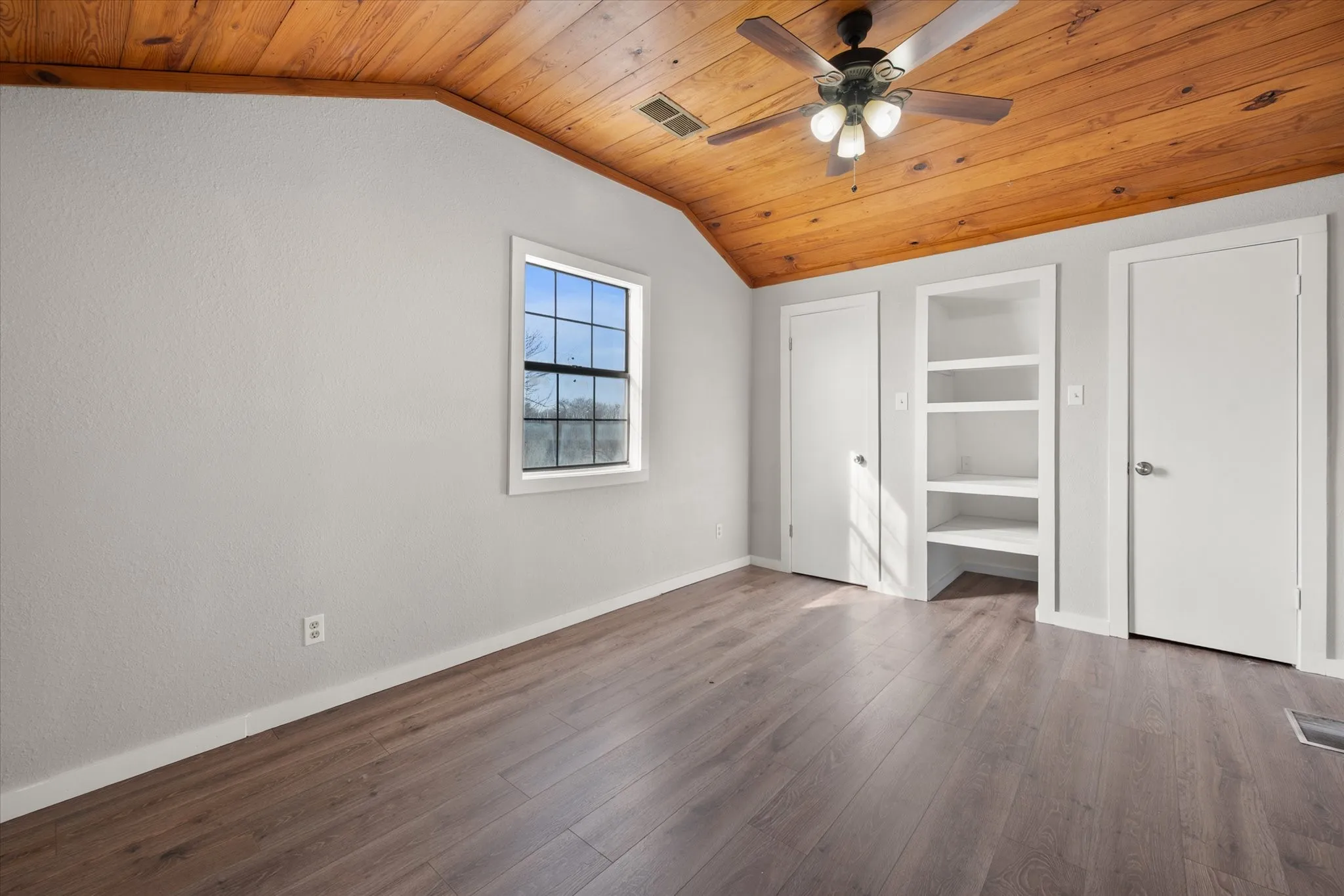 Wood-finish flooring throughout, complemented by a wood-burning stove and a multi-blade ceiling fan