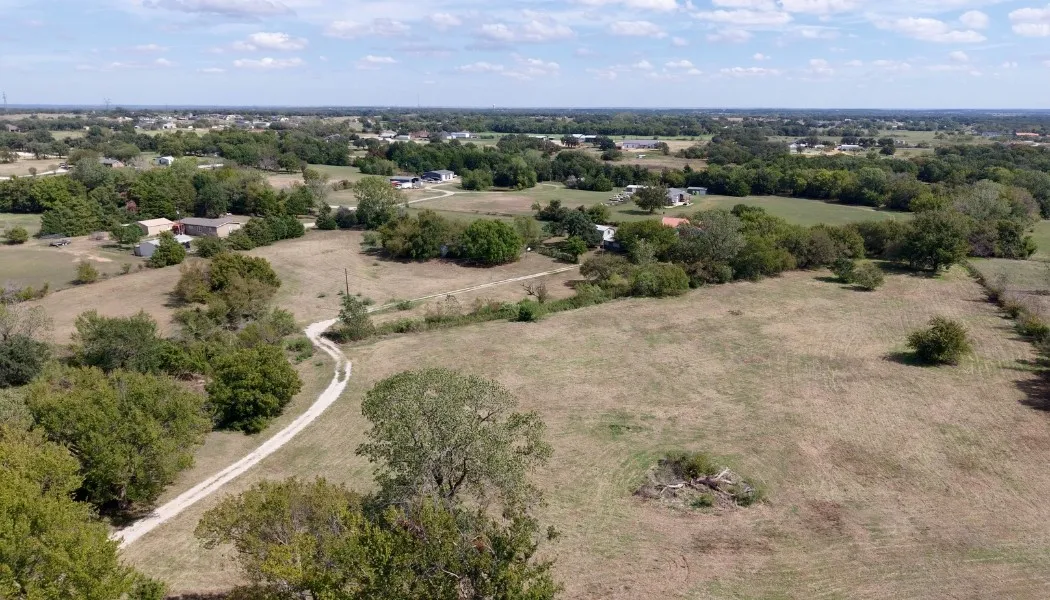 Expansive parcel featuring a winding gravel drive, mature trees, and open fields