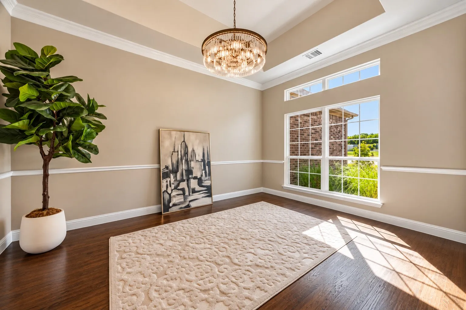 Tray ceiling, drum-style crystal chandelier, wood-finish flooring, and crown molding complemented by chair rail trim