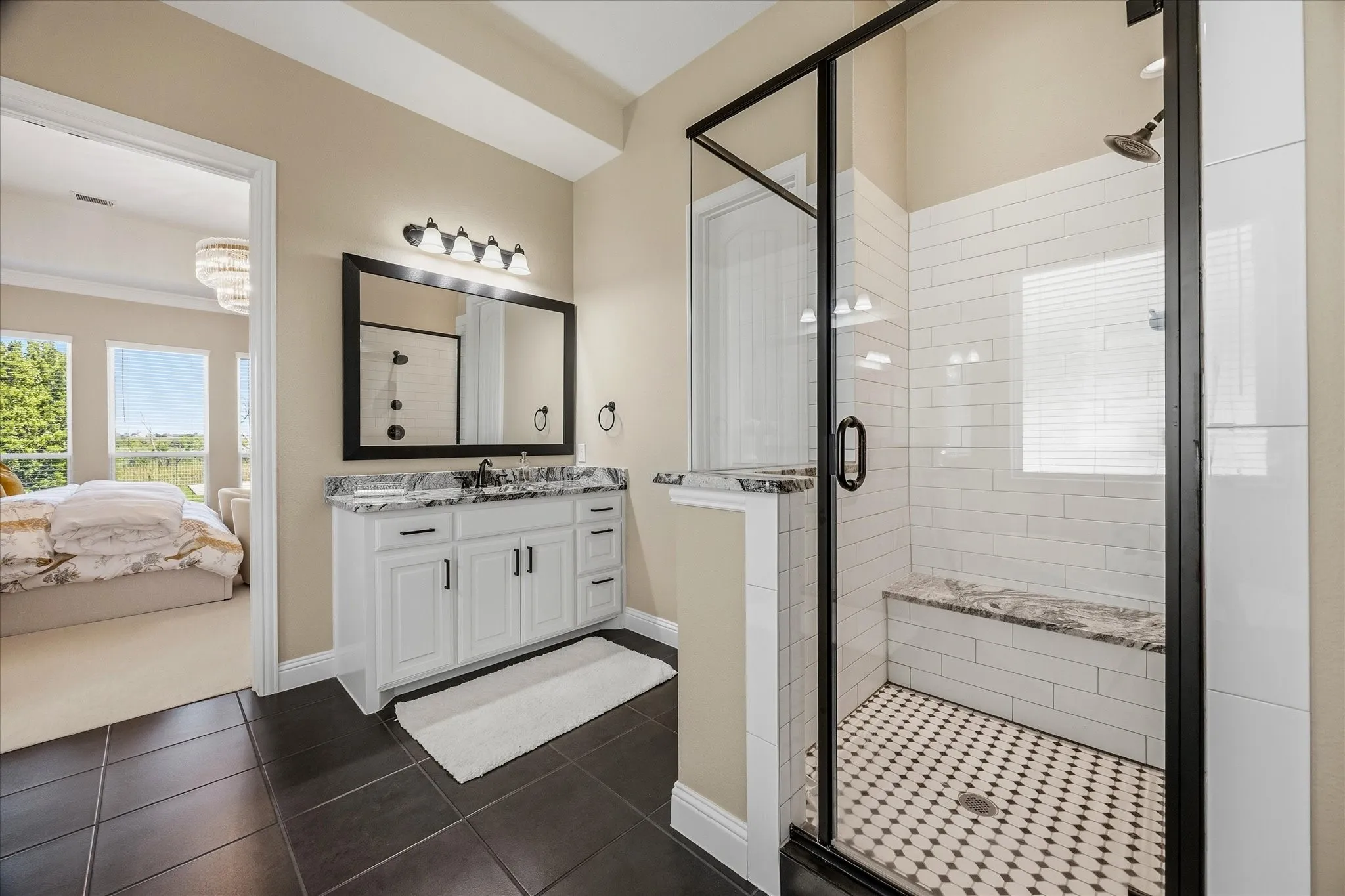 Bathroom featuring a vanity with white cabinetry and dark hardware, a dark-framed mirror, and an attached lighting fixture
