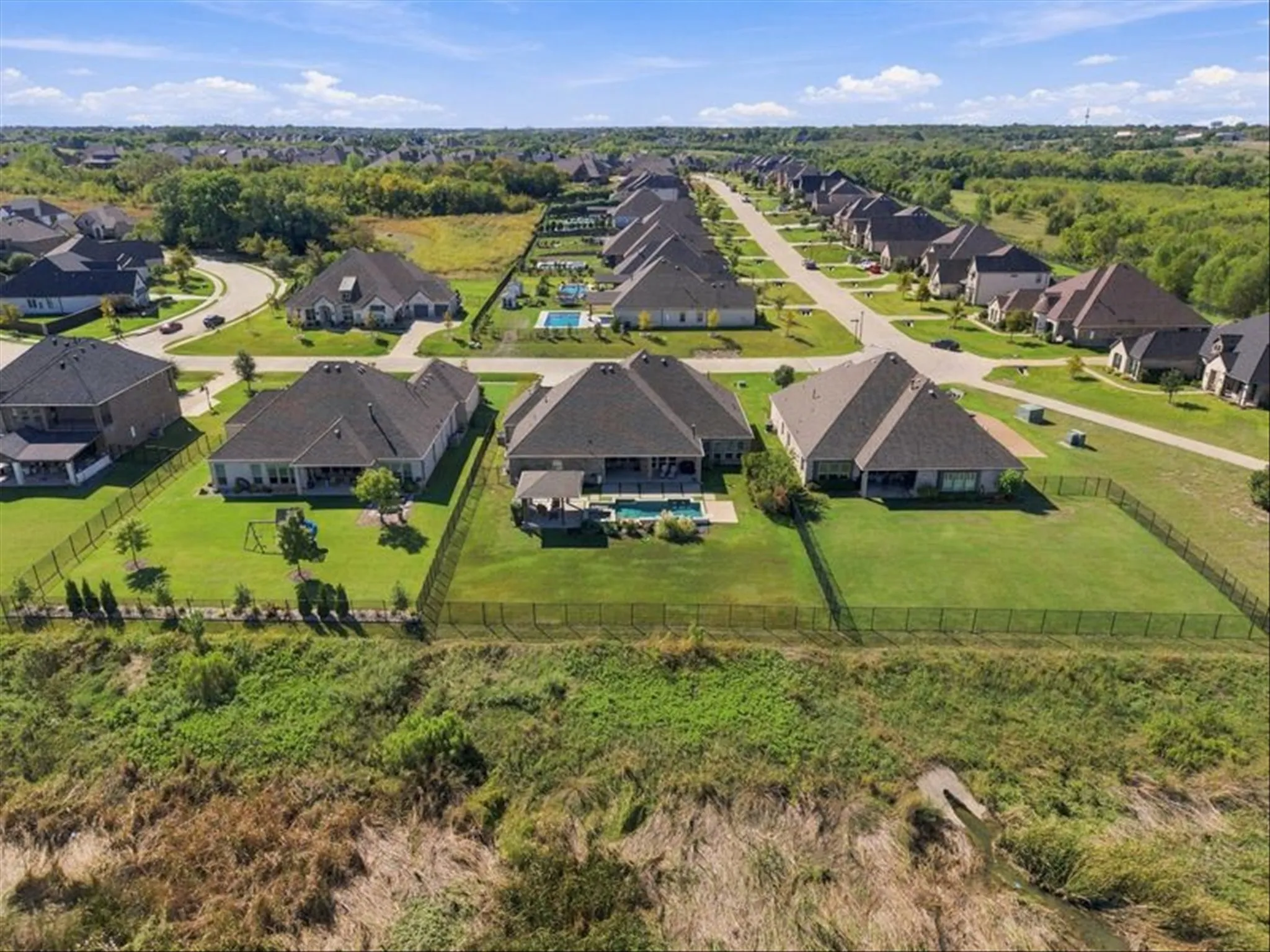 Expansive residential neighborhood with consistent home styles, dark shingle roofs, and private fenced backyards