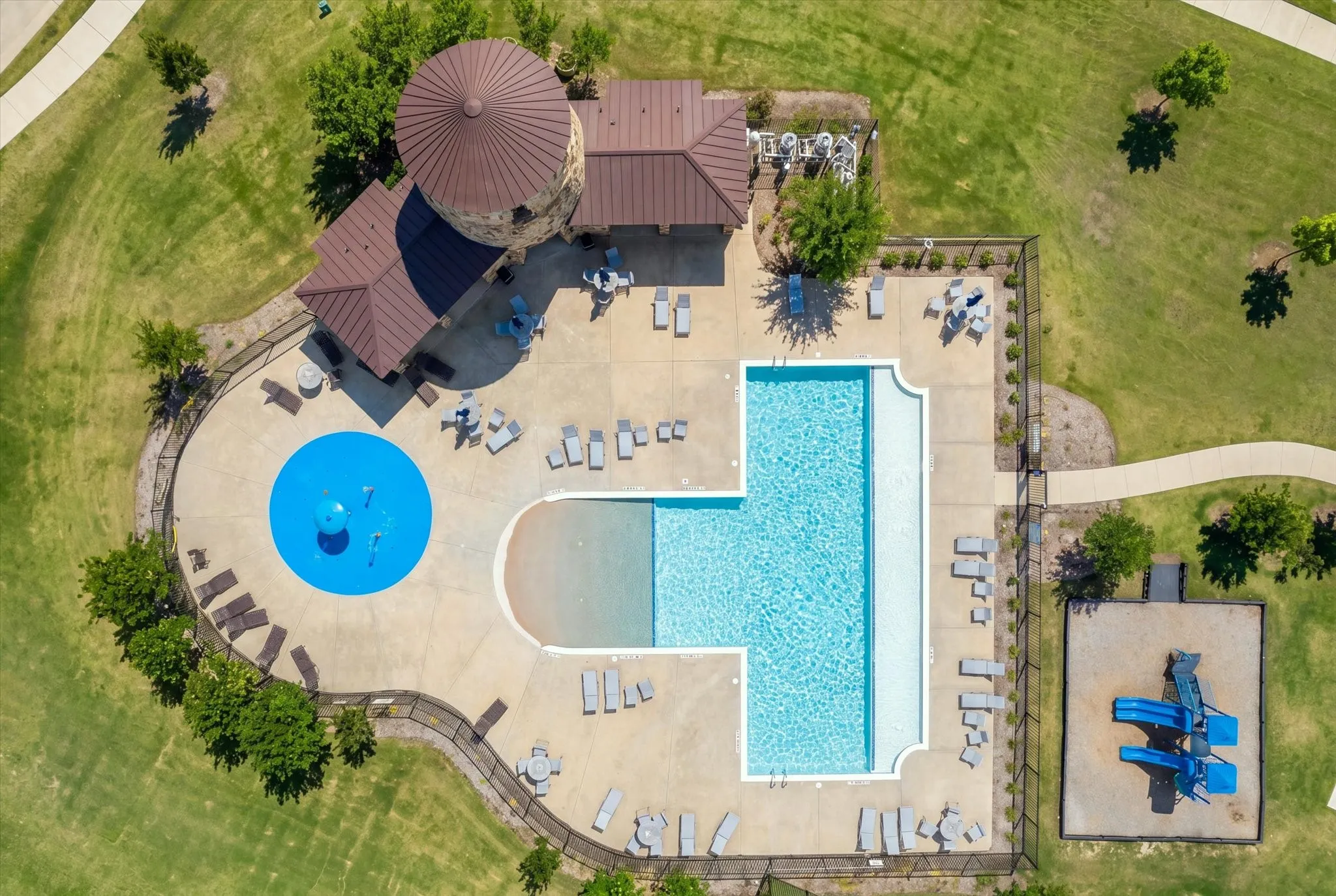 Large swimming pool with integrated shallow entry, adjacent splash pad, and playground structure