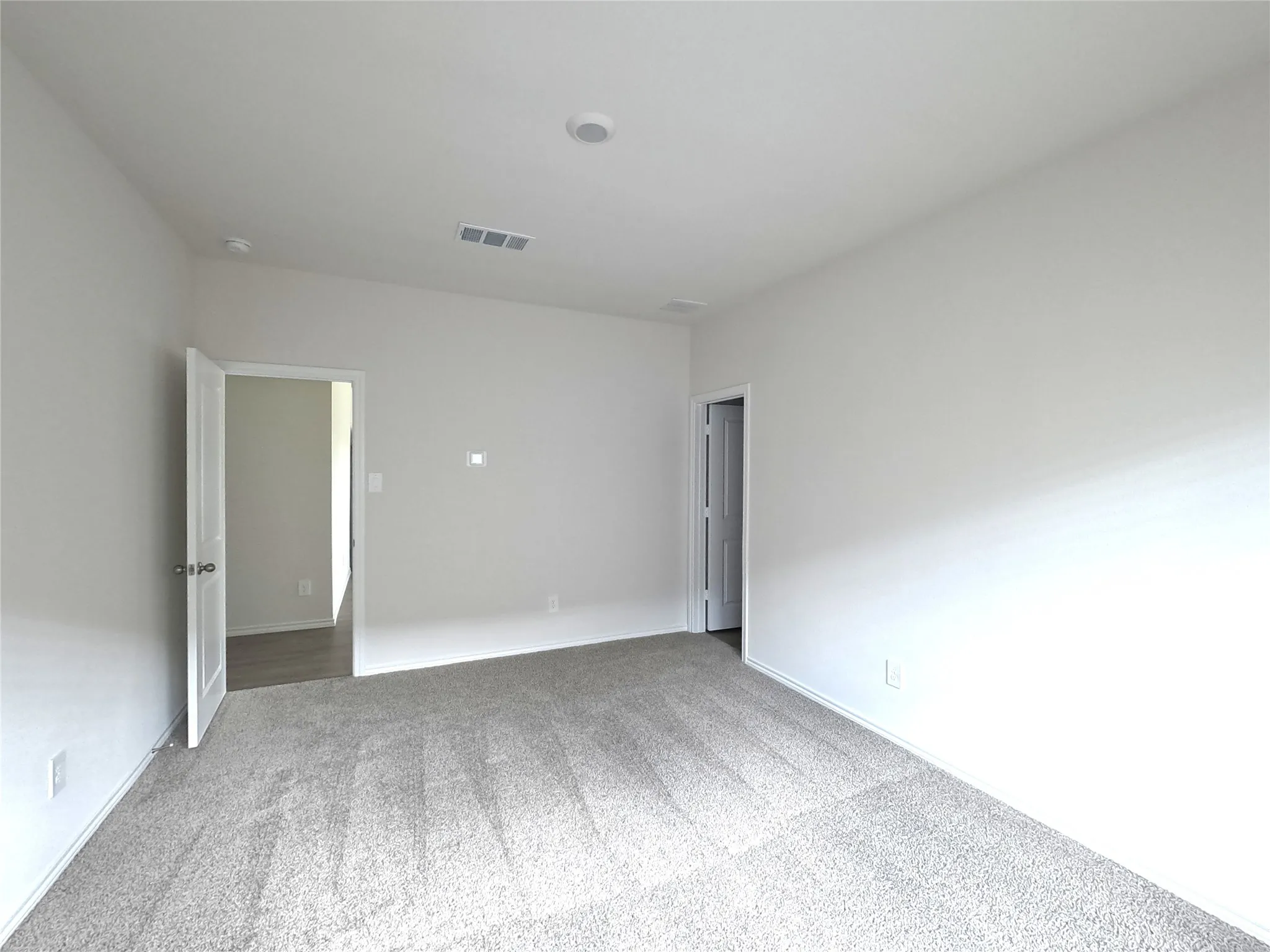 Neutral-toned interior space featuring light-colored wall paint and wall-to-wall carpeting