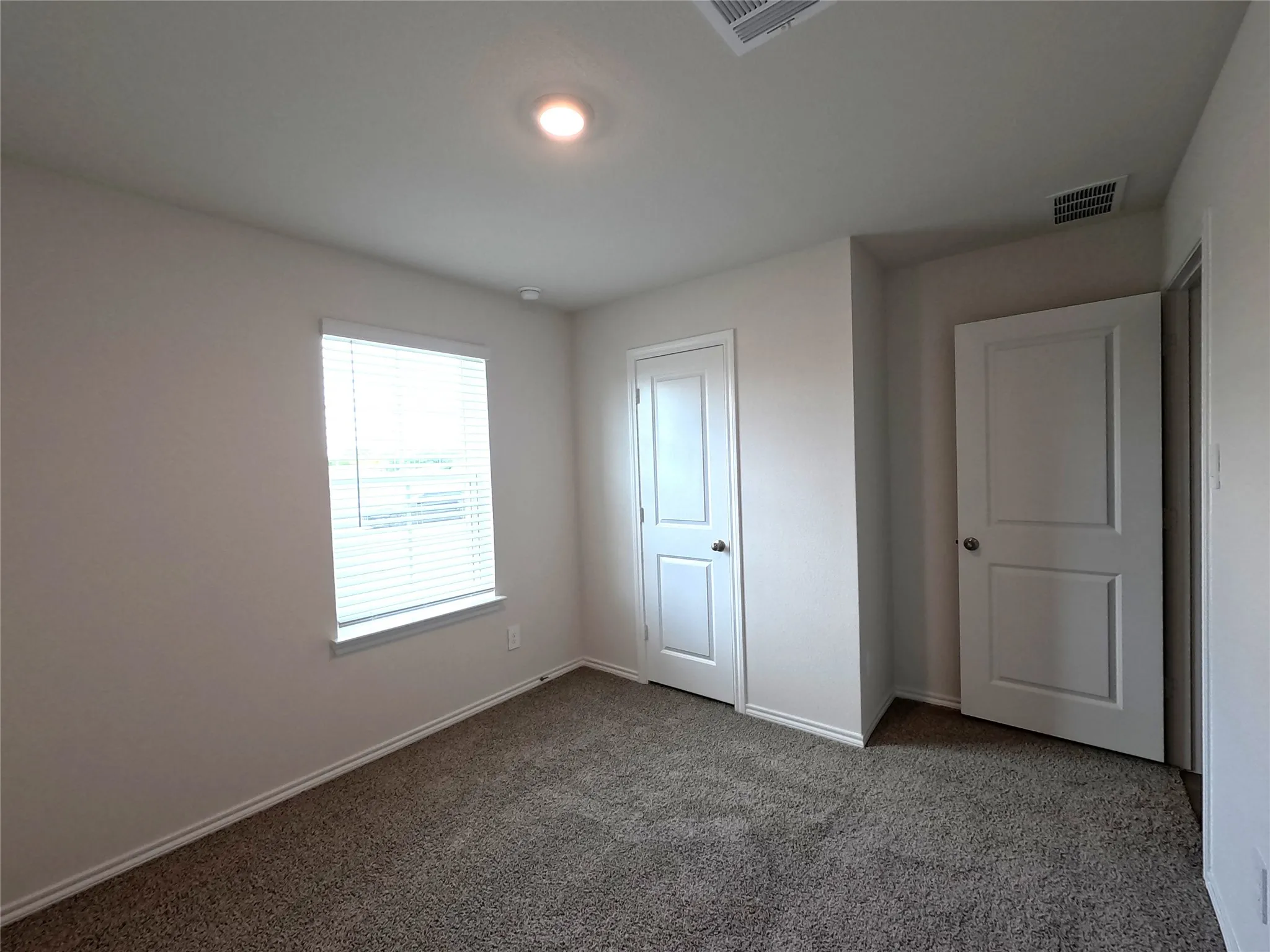 Neutral-toned room featuring neutral wall-to-wall carpeting, white interior doors, and a recessed ceiling light