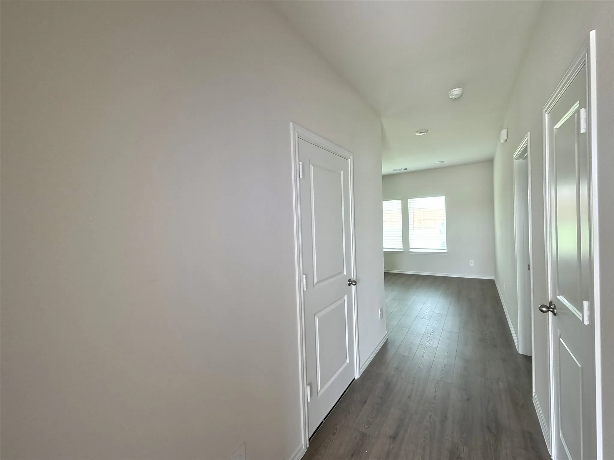 Hallway featuring wood-finish flooring, white panel interior doors, and recessed ceiling lighting