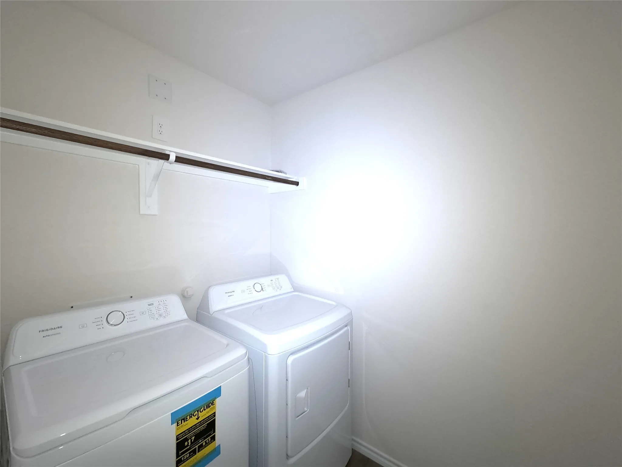 Dedicated laundry area featuring white appliances and a wall-mounted storage shelf