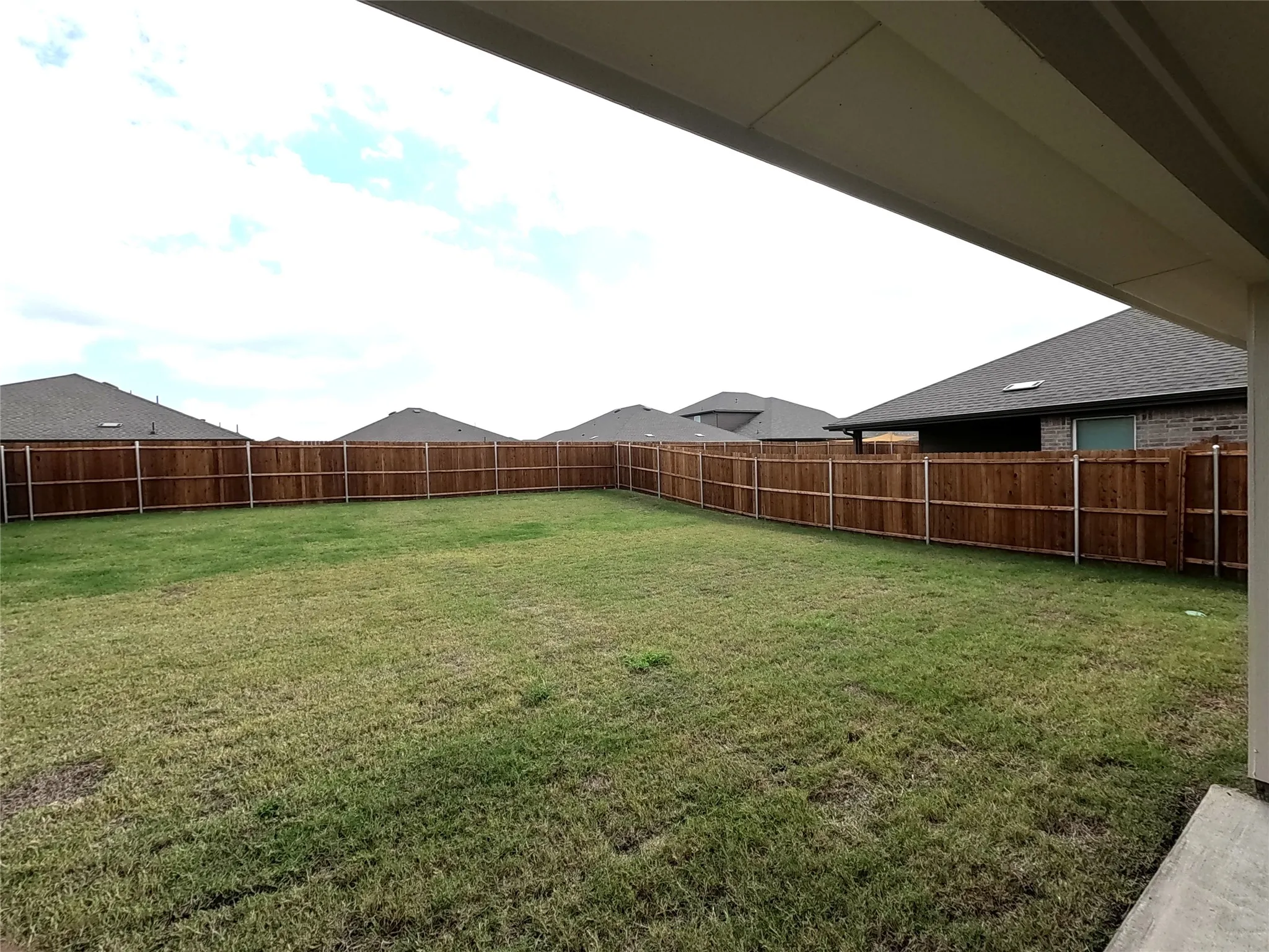 Backyard featuring a grass lawn, full-height wood fencing, and a concrete patio slab