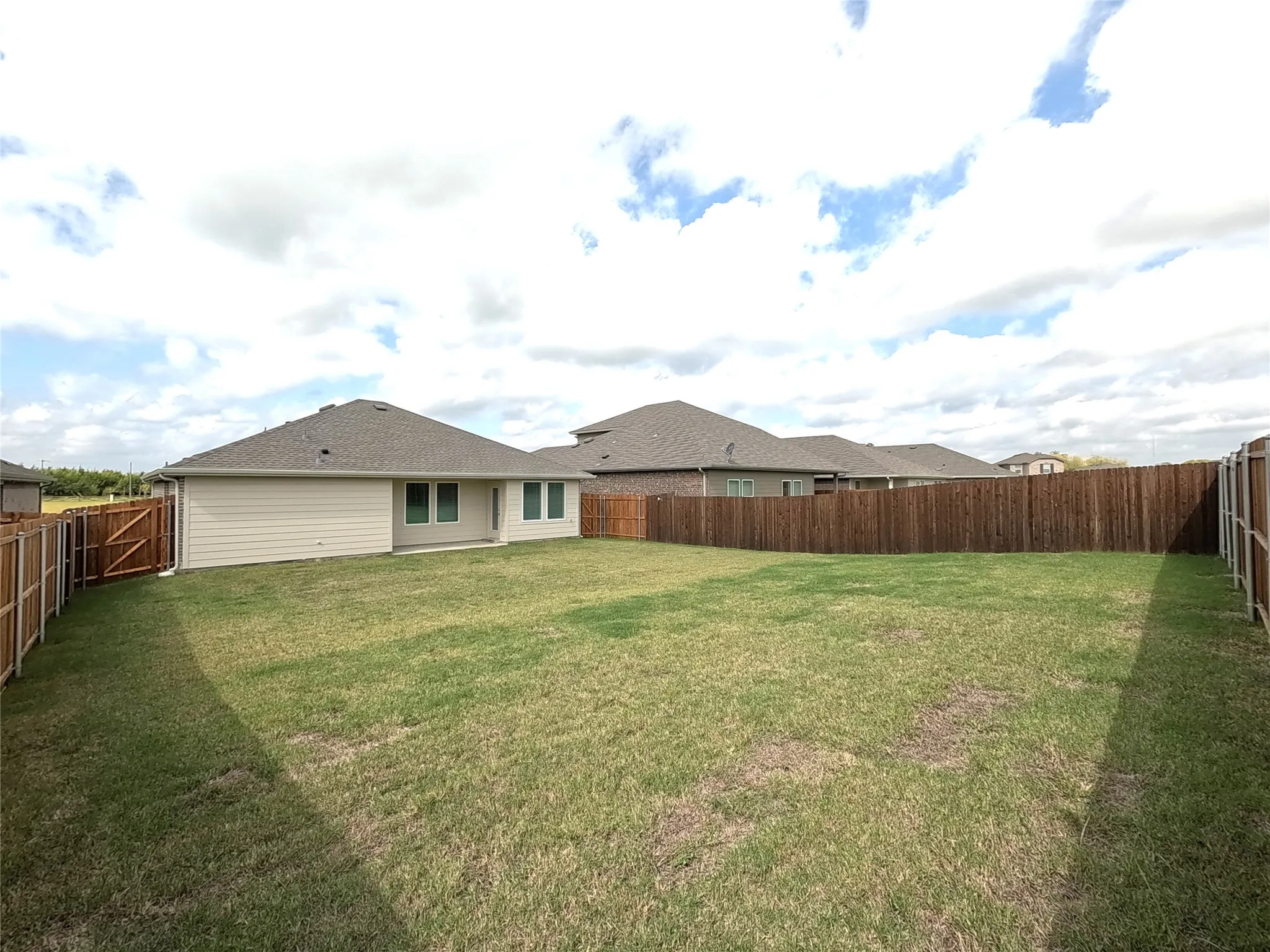 Expansive backyard featuring a level lawn and full-perimeter wood fencing