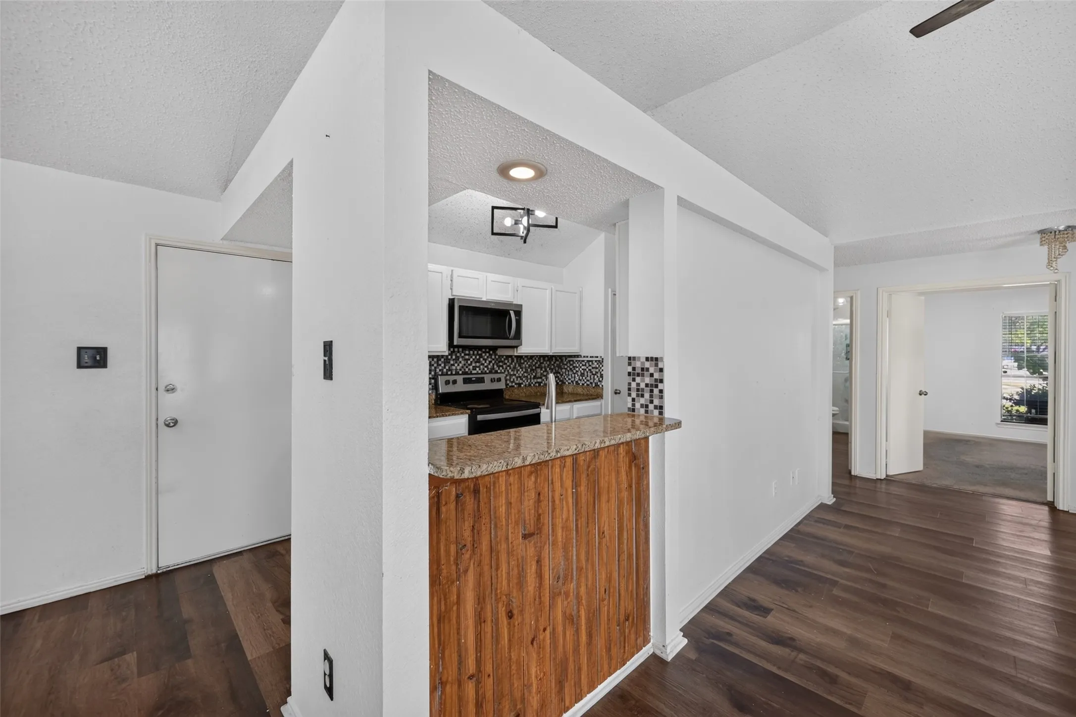 Wood-finish flooring throughout, with a breakfast bar featuring a stone-look countertop and wood-paneled base