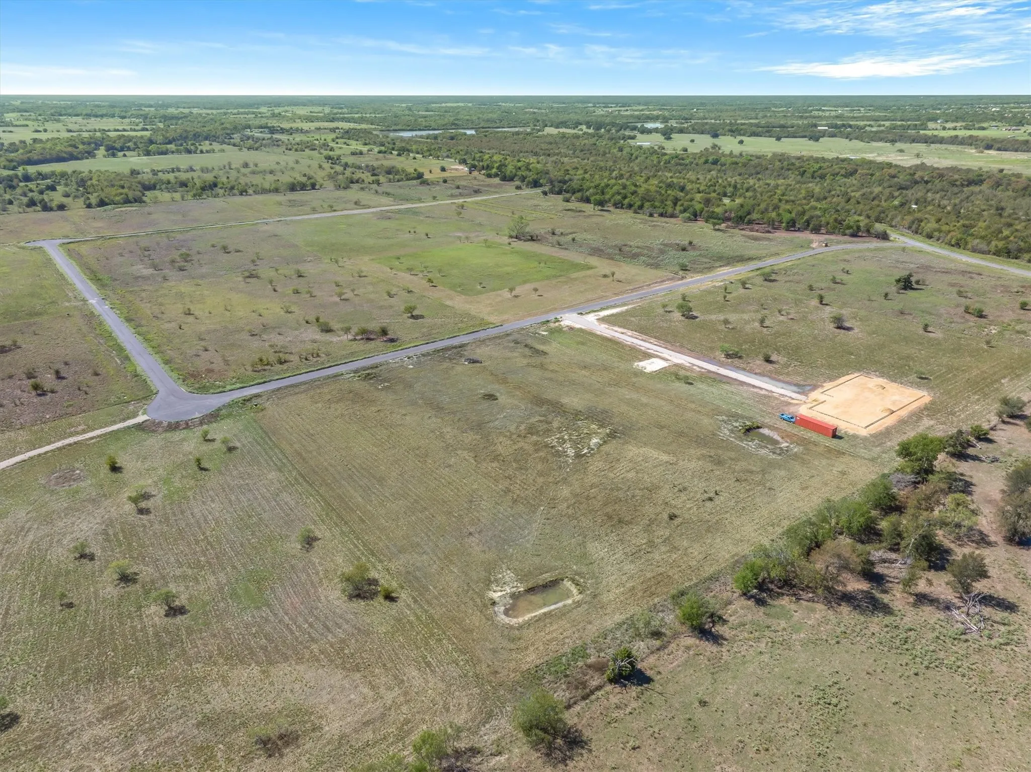 Expansive acreage with established roadways, clear build sites, and a small pond feature