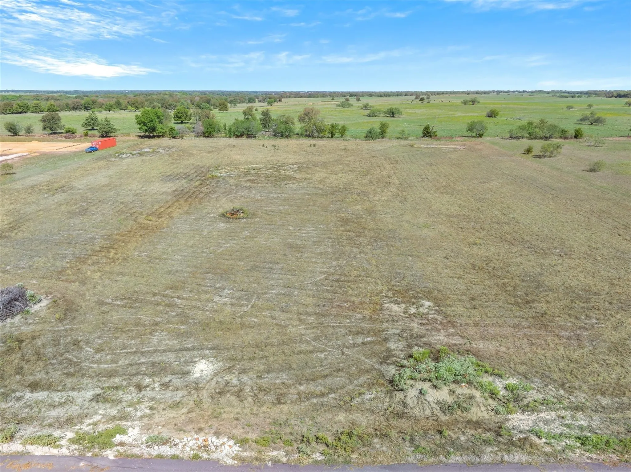 Expansive open land with varied ground cover and distant tree lines