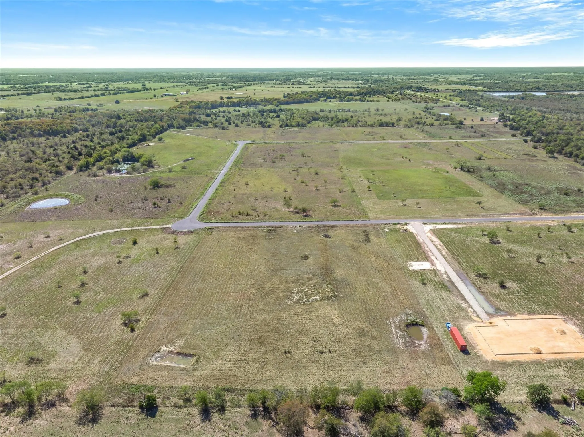 Expansive land parcel featuring clearings, established access roads, and multiple water features