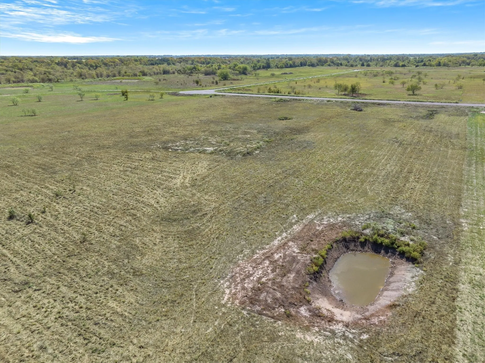 Expansive open land featuring a water retention pond and natural vegetation