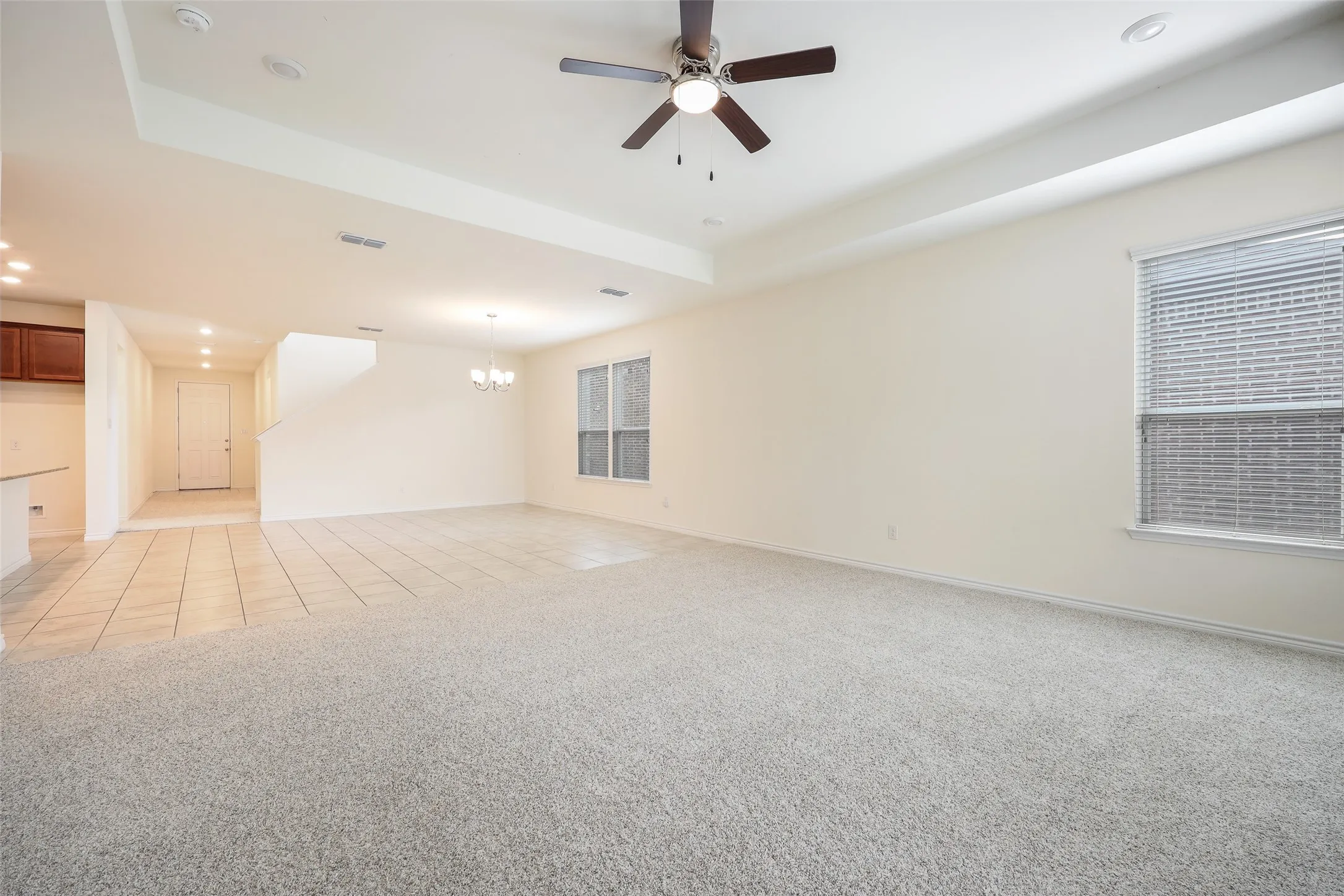 Tray ceiling with recessed lighting, central ceiling fan, neutral wall-to-wall carpeting, and tiled flooring