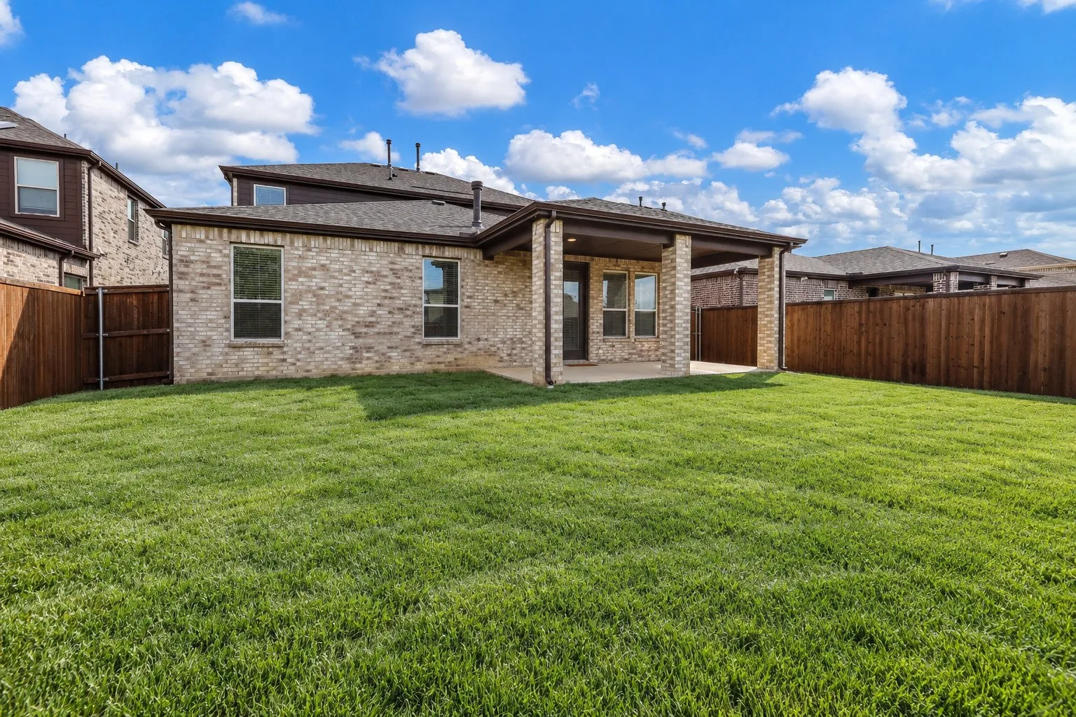 Virtually improved image. Brick exterior, covered rear patio, and expansive lawn enclosed by wood privacy fencing