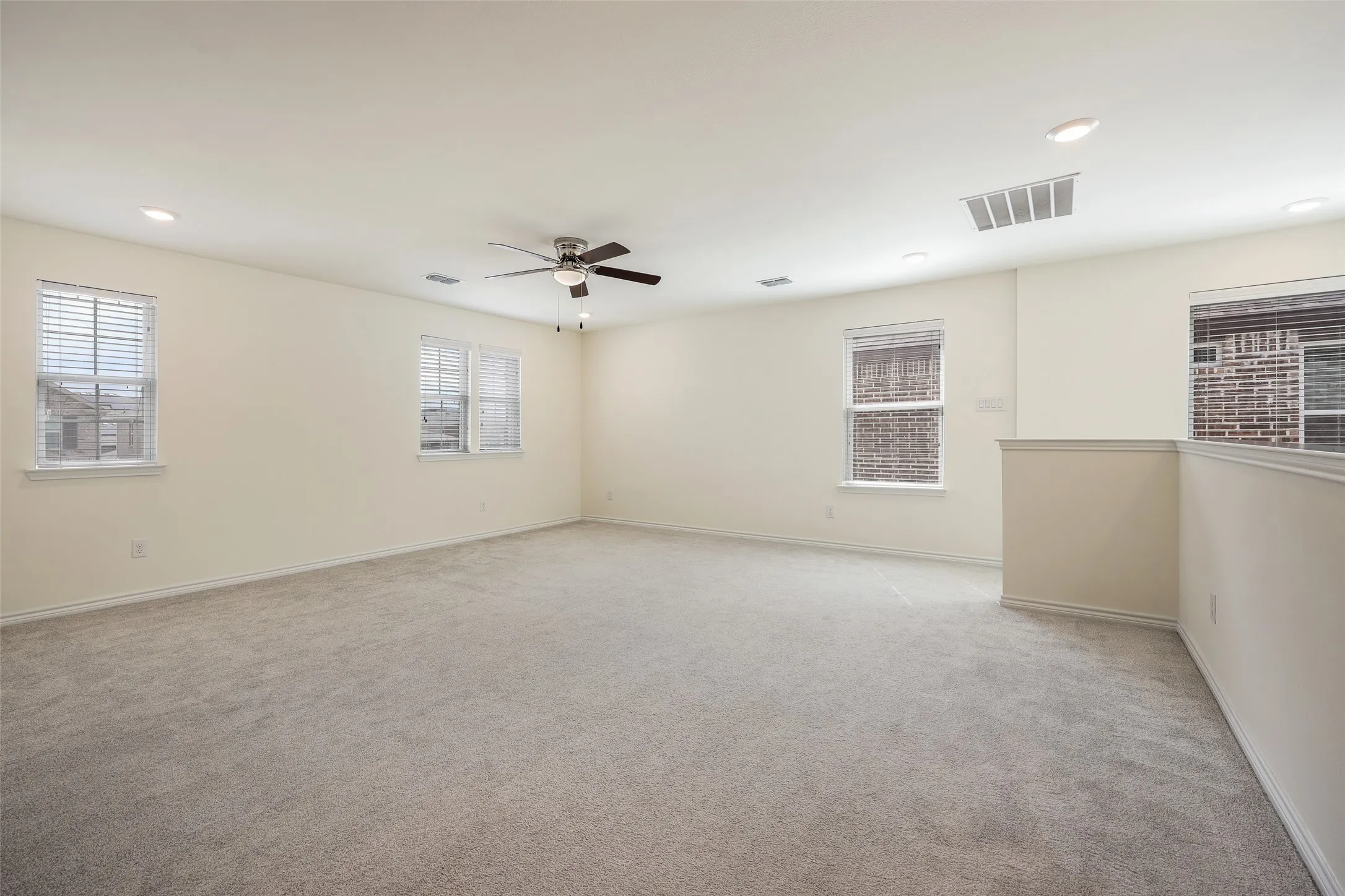 Neutral interior featuring wall-to-wall carpeting, multiple windows, recessed lighting, and a ceiling fan