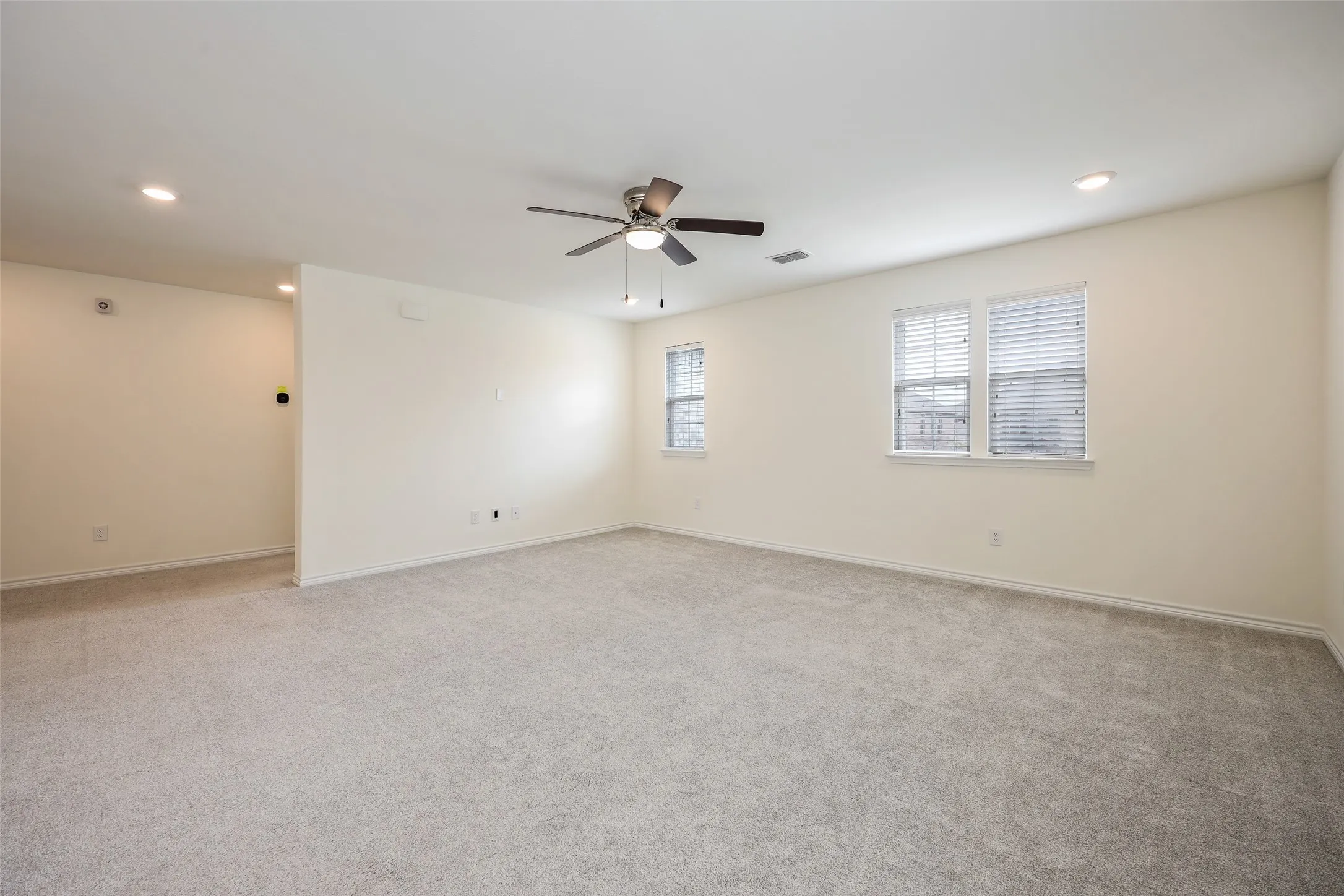Interior space featuring neutral wall-to-wall carpeting, recessed lighting, and a multi-blade ceiling fan