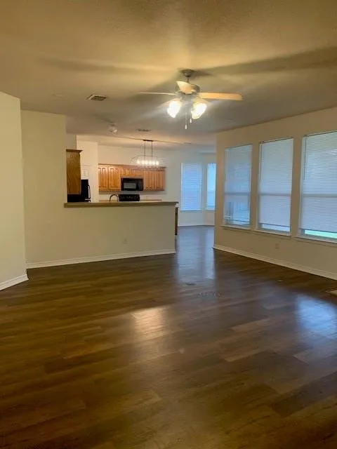 Wood-finish flooring, multi-pane windows, ceiling fan with integrated light fixture, kitchen peninsula, and wood cabinetry