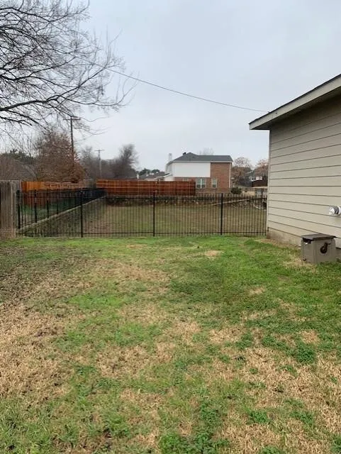 Backyard area featuring metal perimeter fencing, wood-paneled privacy fencing, and horizontal lap siding