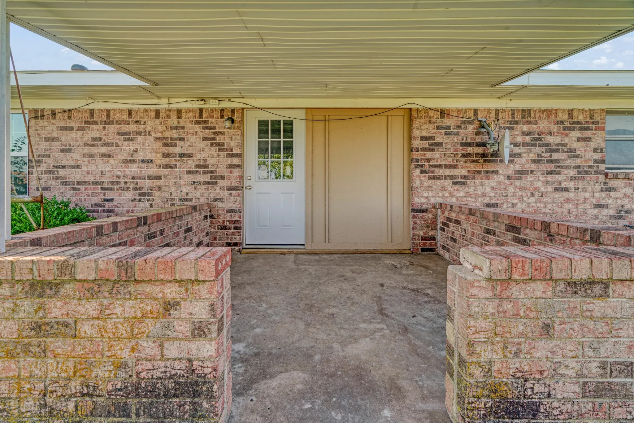 Property entrance featuring brick siding and a patio