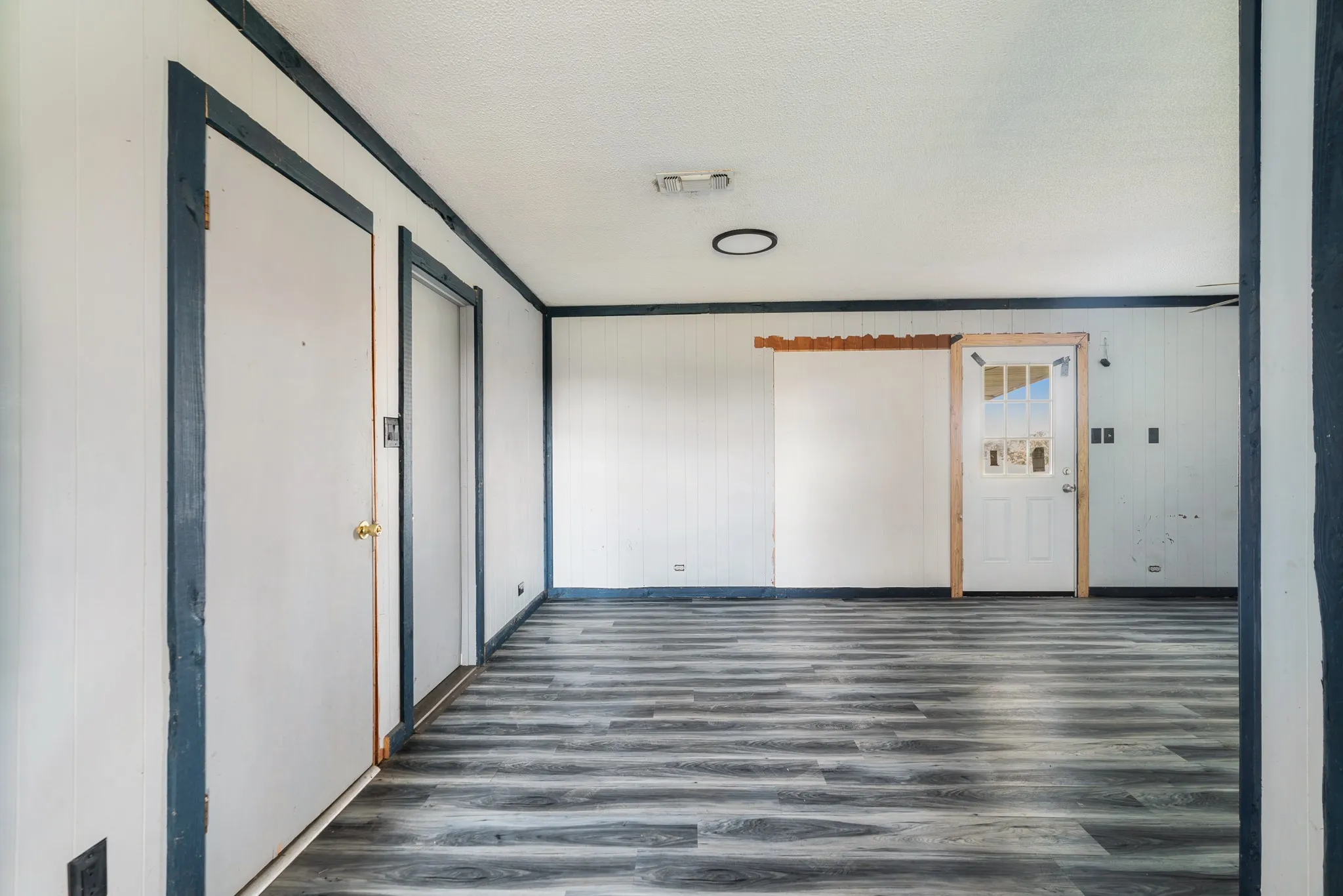 Spare room featuring dark wood-type flooring, a textured ceiling, and crown molding