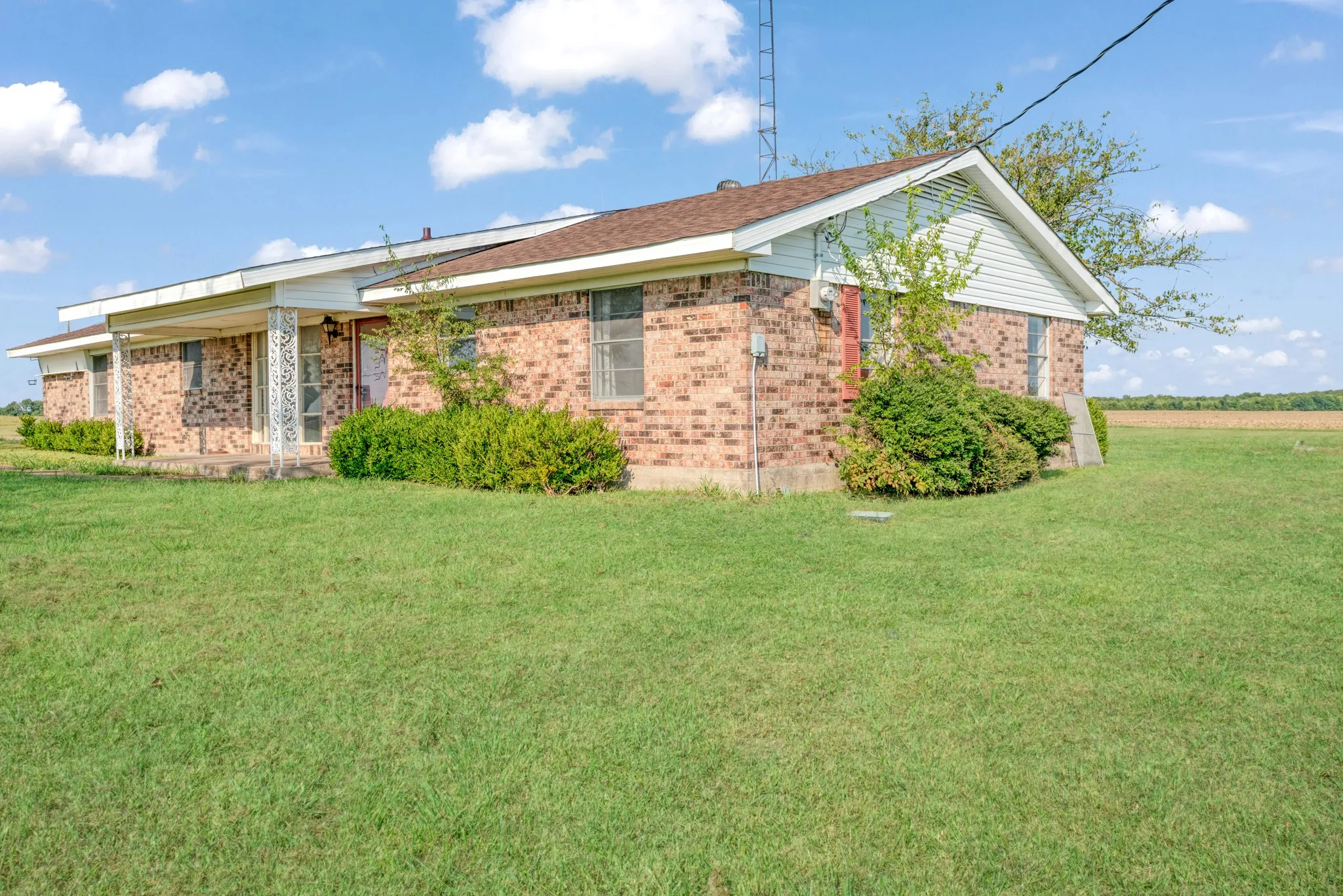 Back of property featuring a lawn and brick siding
