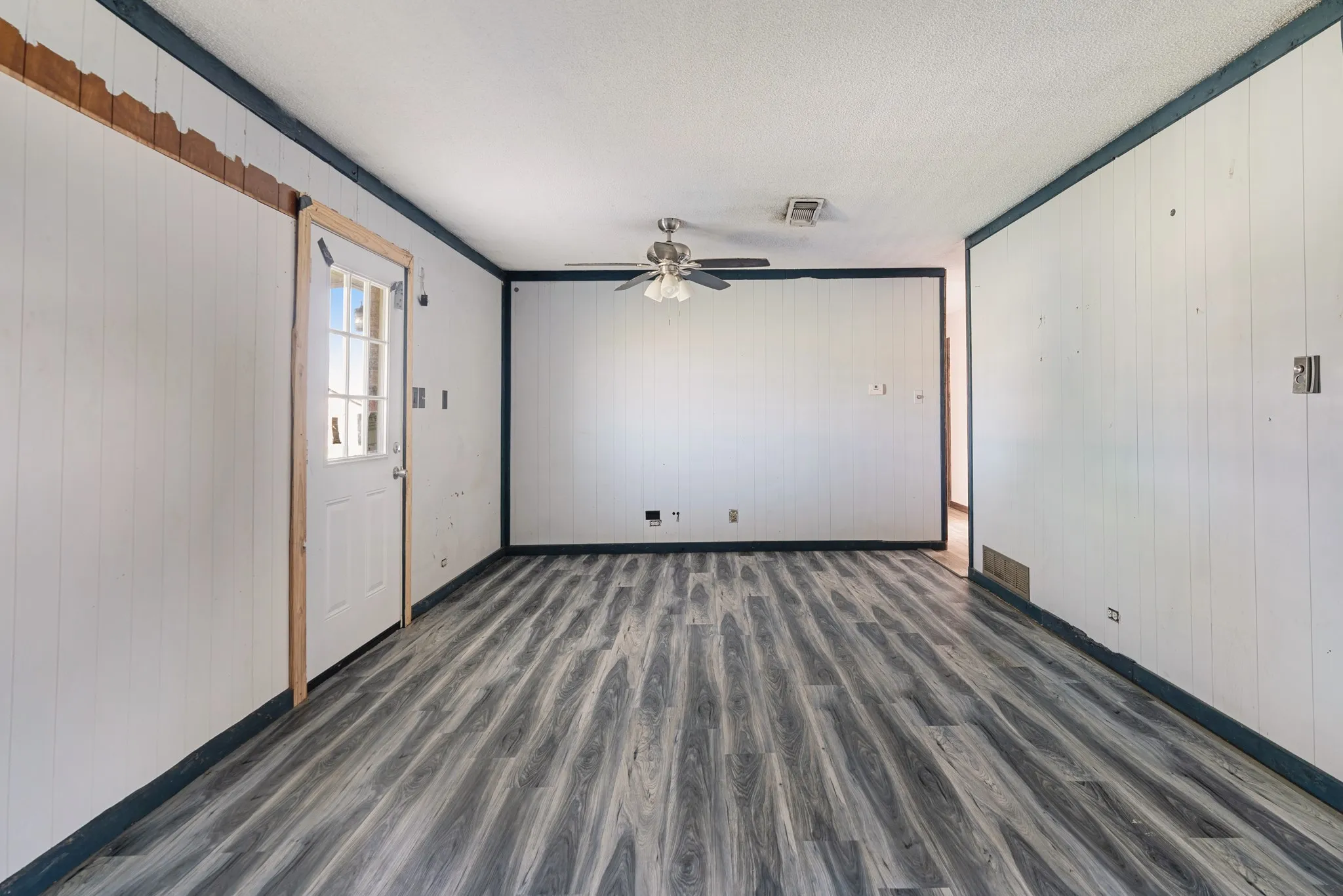Spare room with dark wood finished floors, wood walls, and a ceiling fan