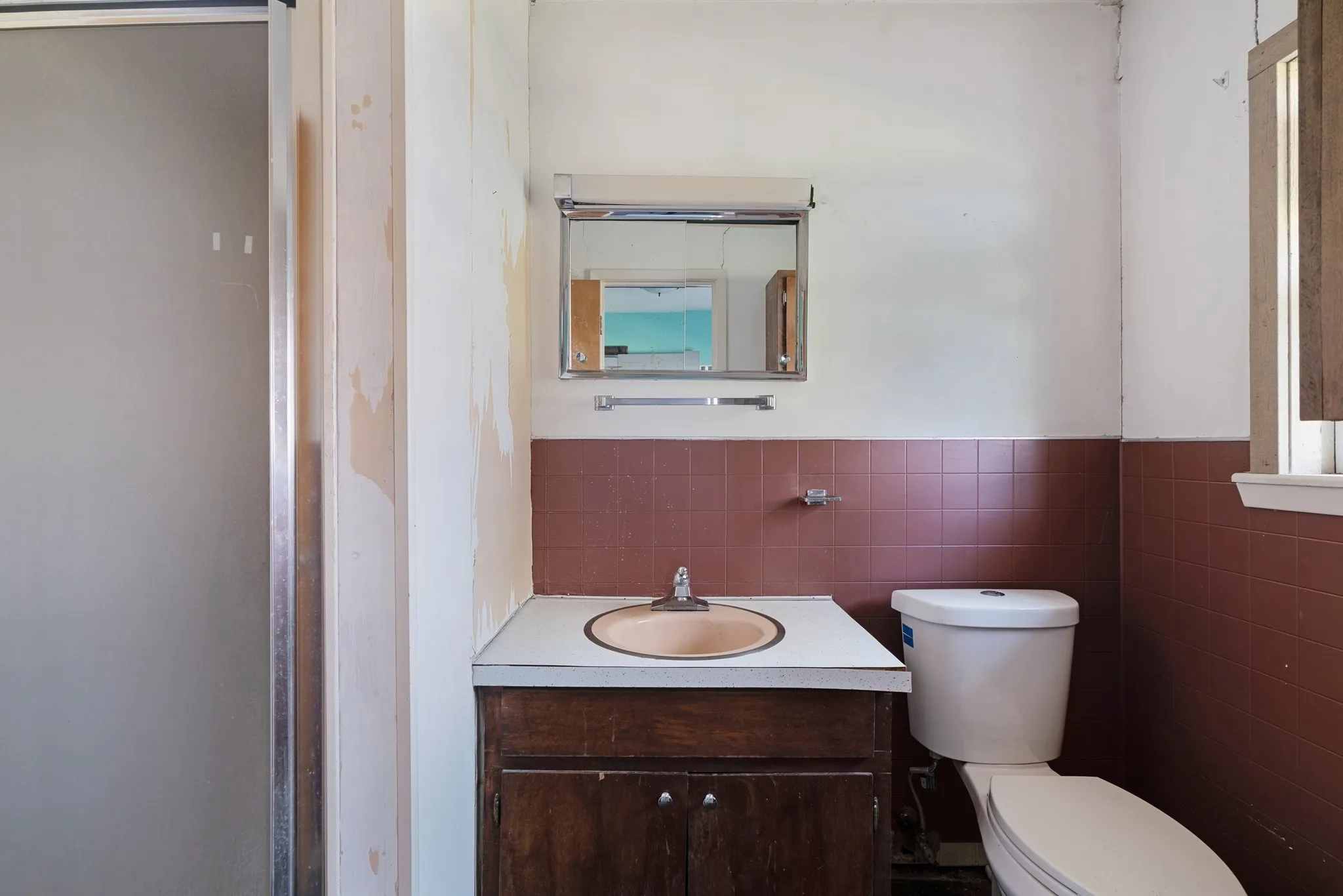 Half bathroom featuring vanity, tile walls, and wainscoting