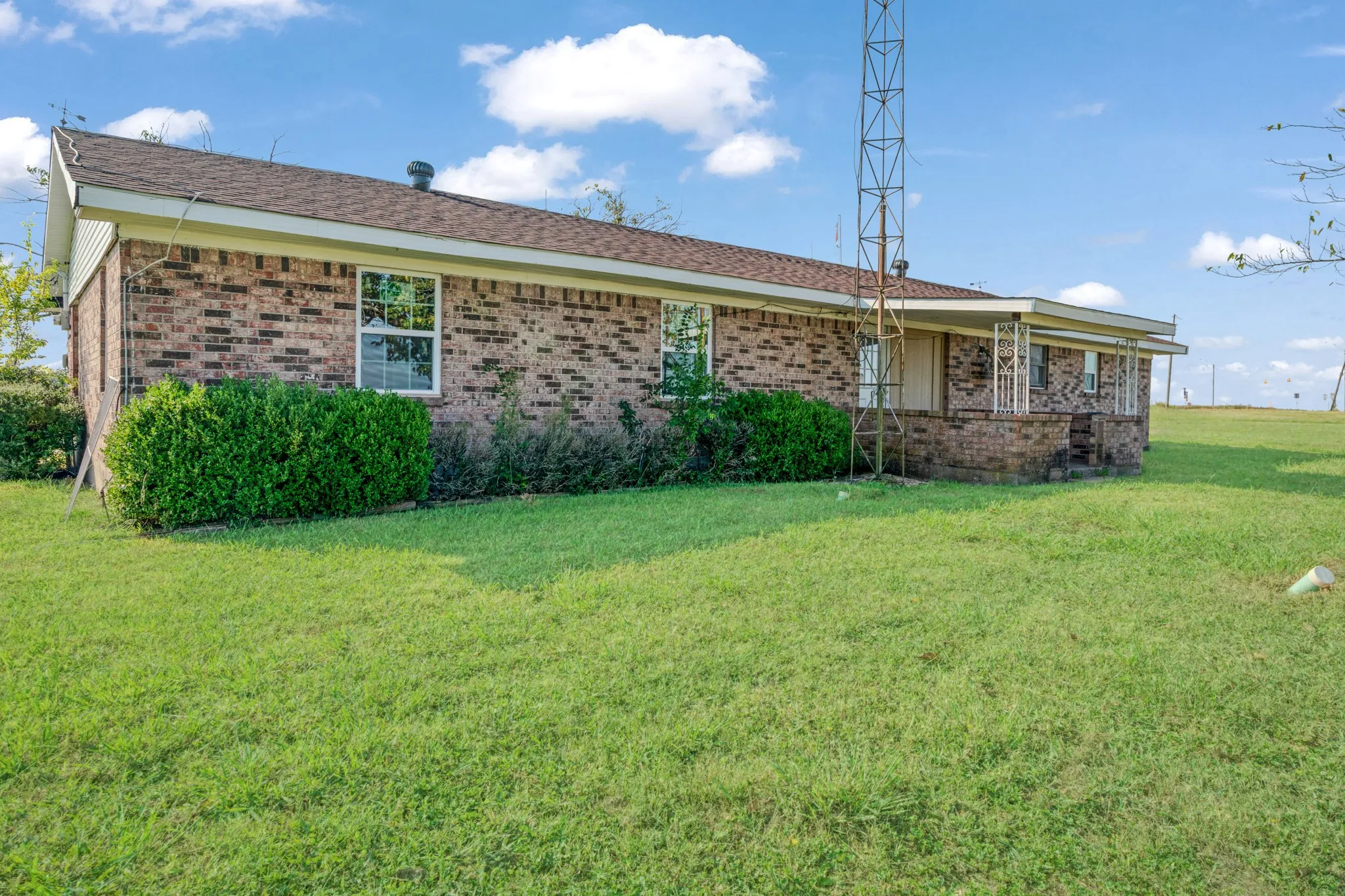 View of front of house featuring a front lawn, brick siding, and covered porch