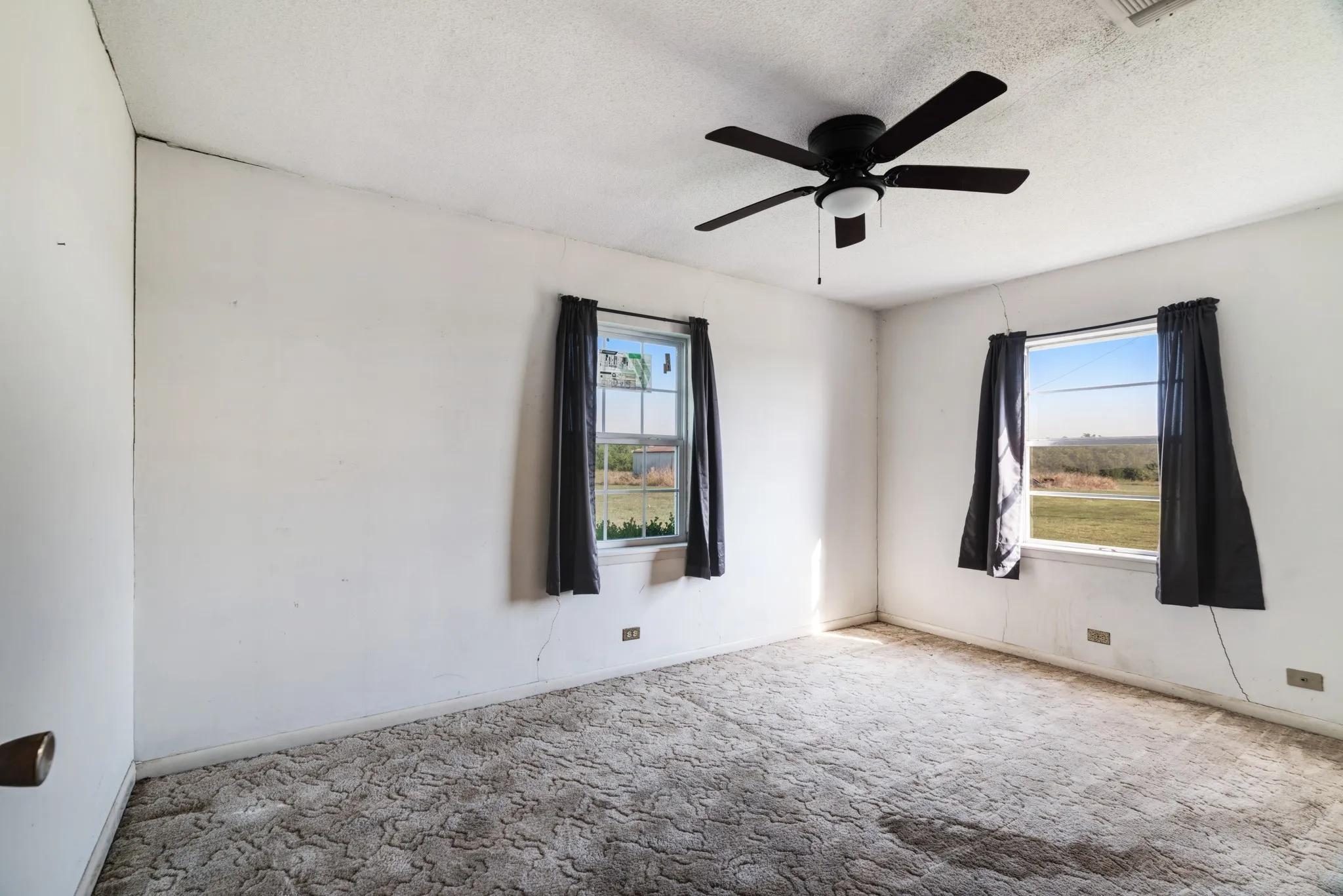 Carpeted empty room with healthy amount of natural light, a ceiling fan, and a textured ceiling
