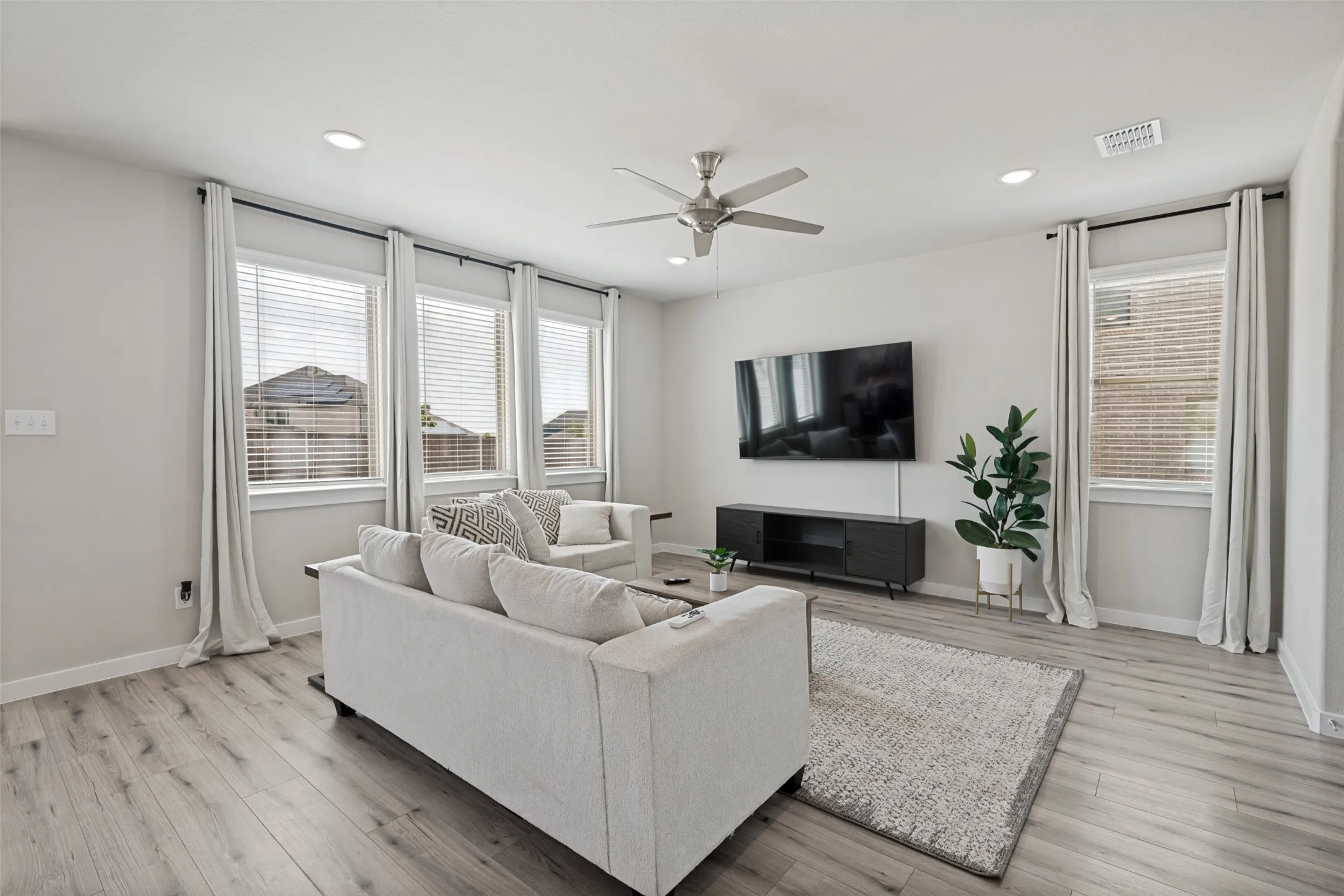Wood-finish flooring, recessed lighting, ceiling fan, and large windows with horizontal blinds